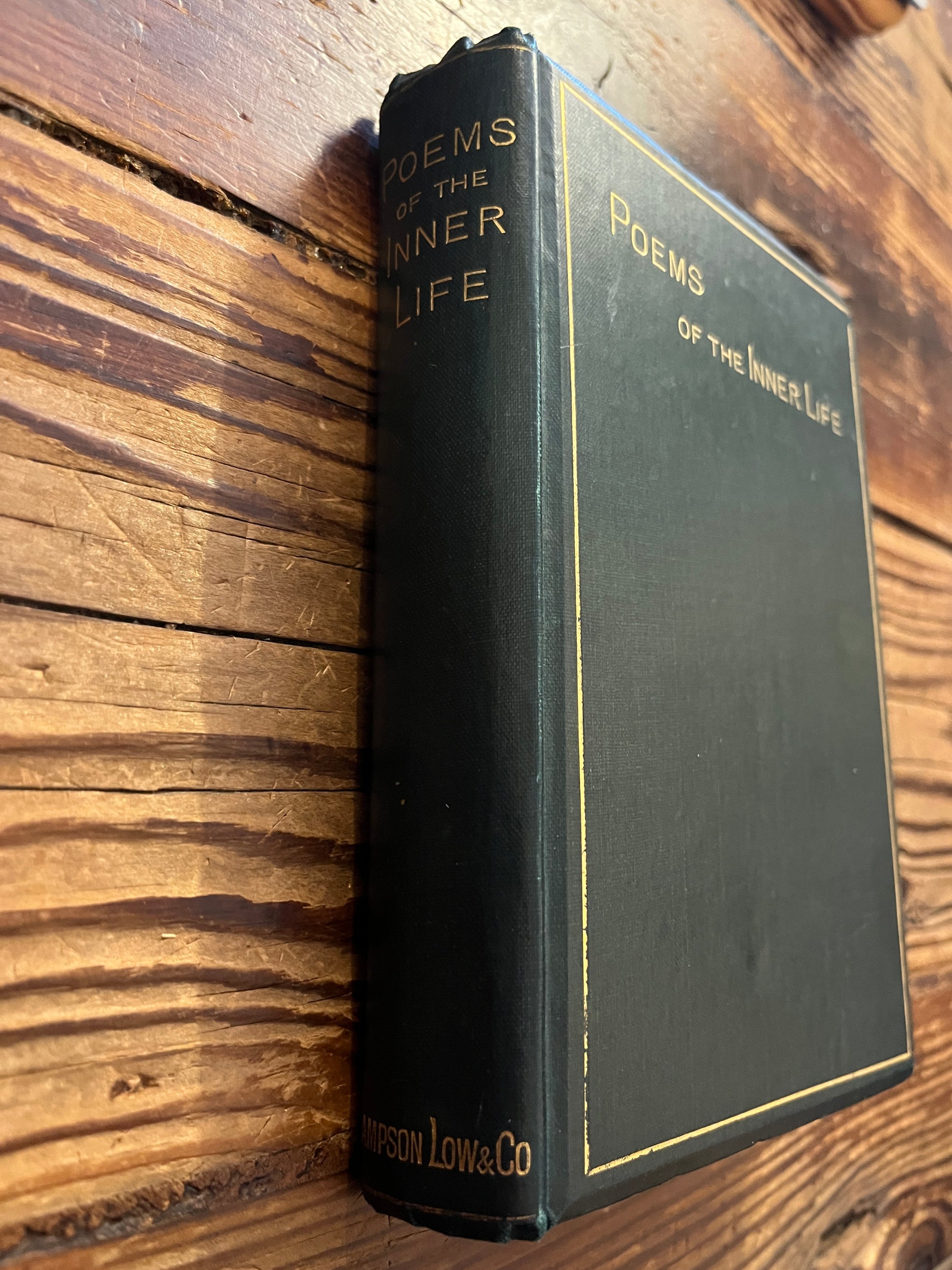 Spine of book titled 'Poems of the Inner Life' on a wooden surface