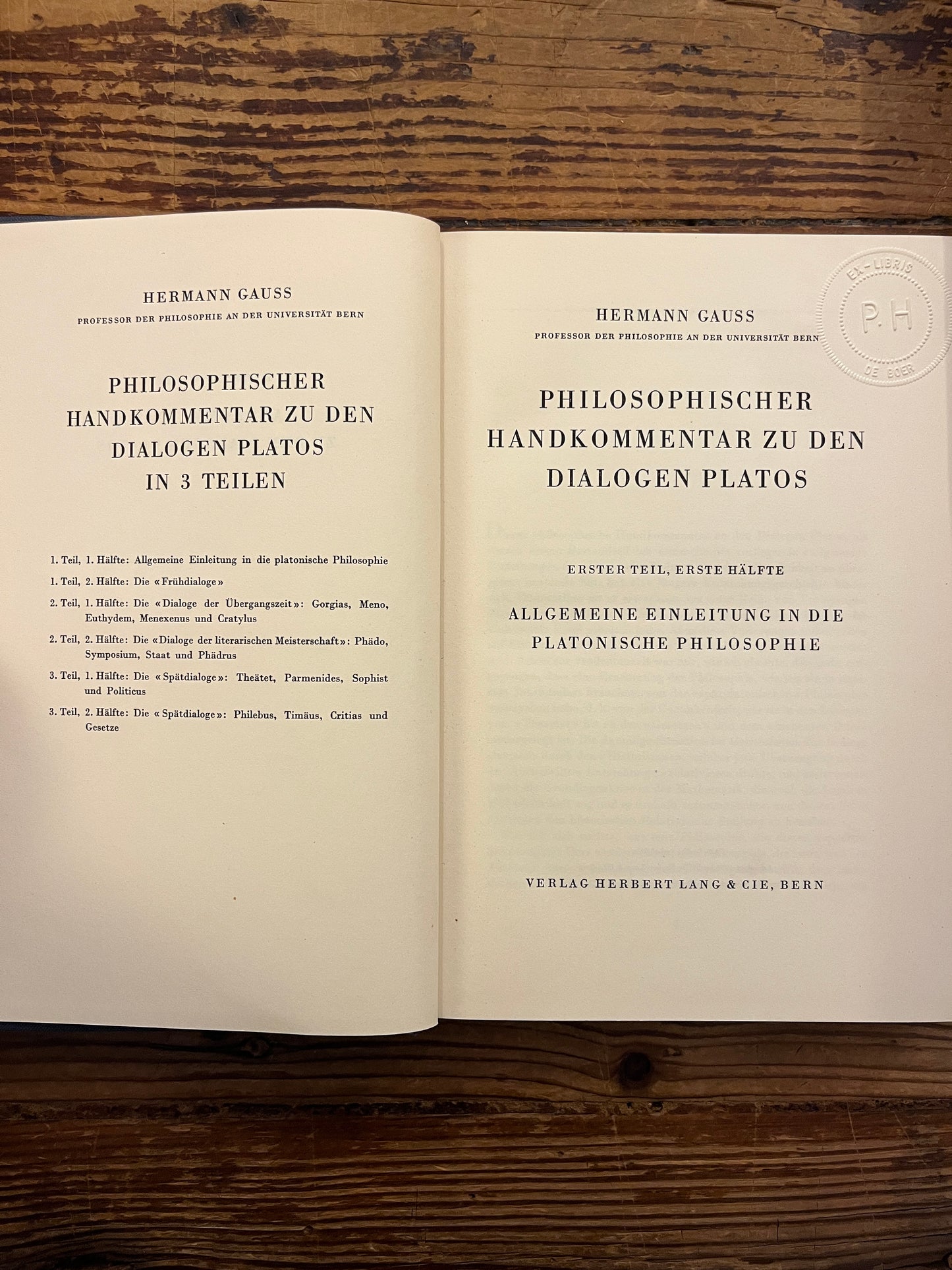 Open book titled 'Philosophischer Handkommentar zu den Dialogen Platos' by H. Gauss on a wooden surface 