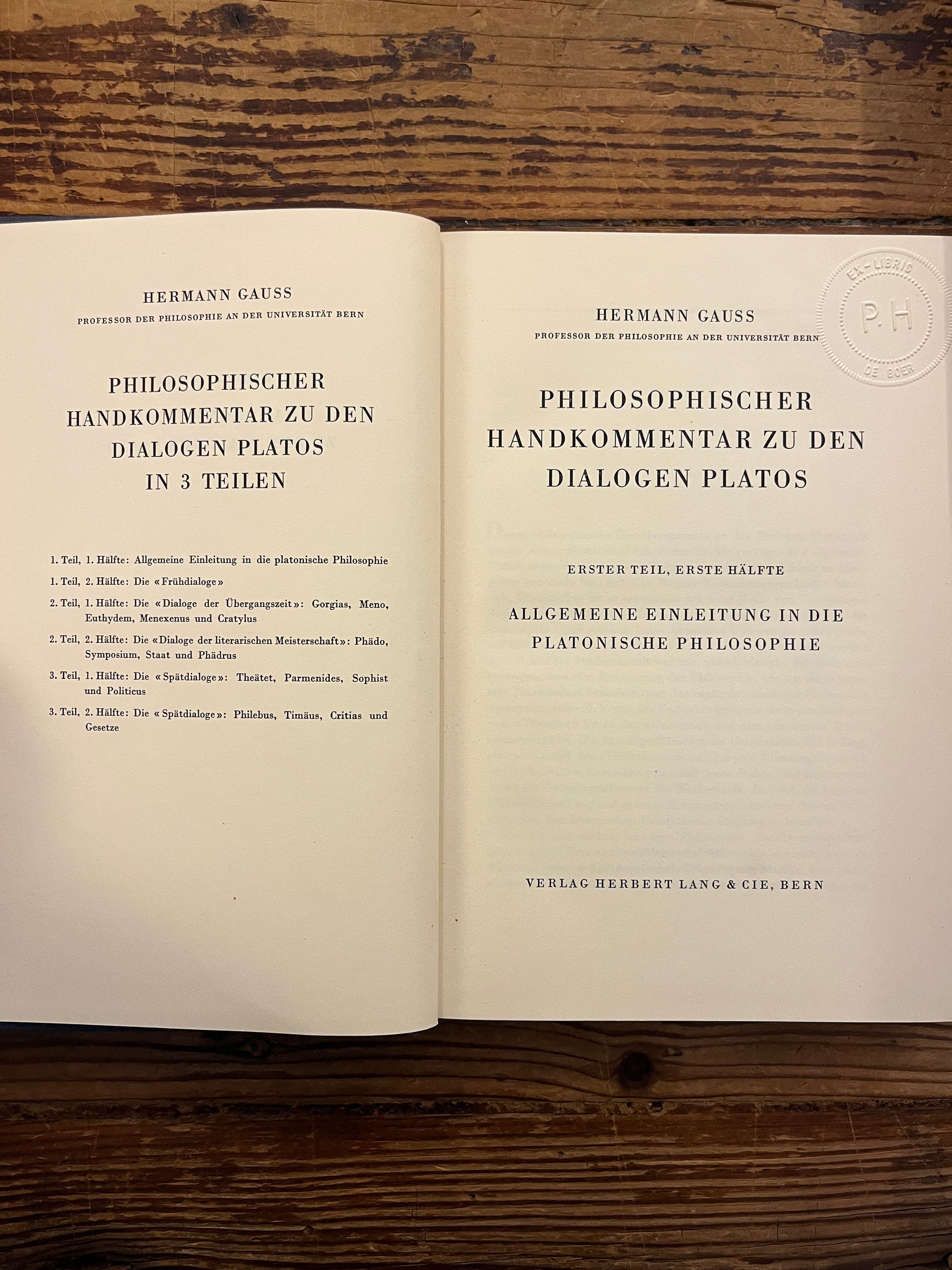 Open book titled 'Philosophischer Handkommentar zu den Dialogen Platos' by H. Gauss on a wooden surface 