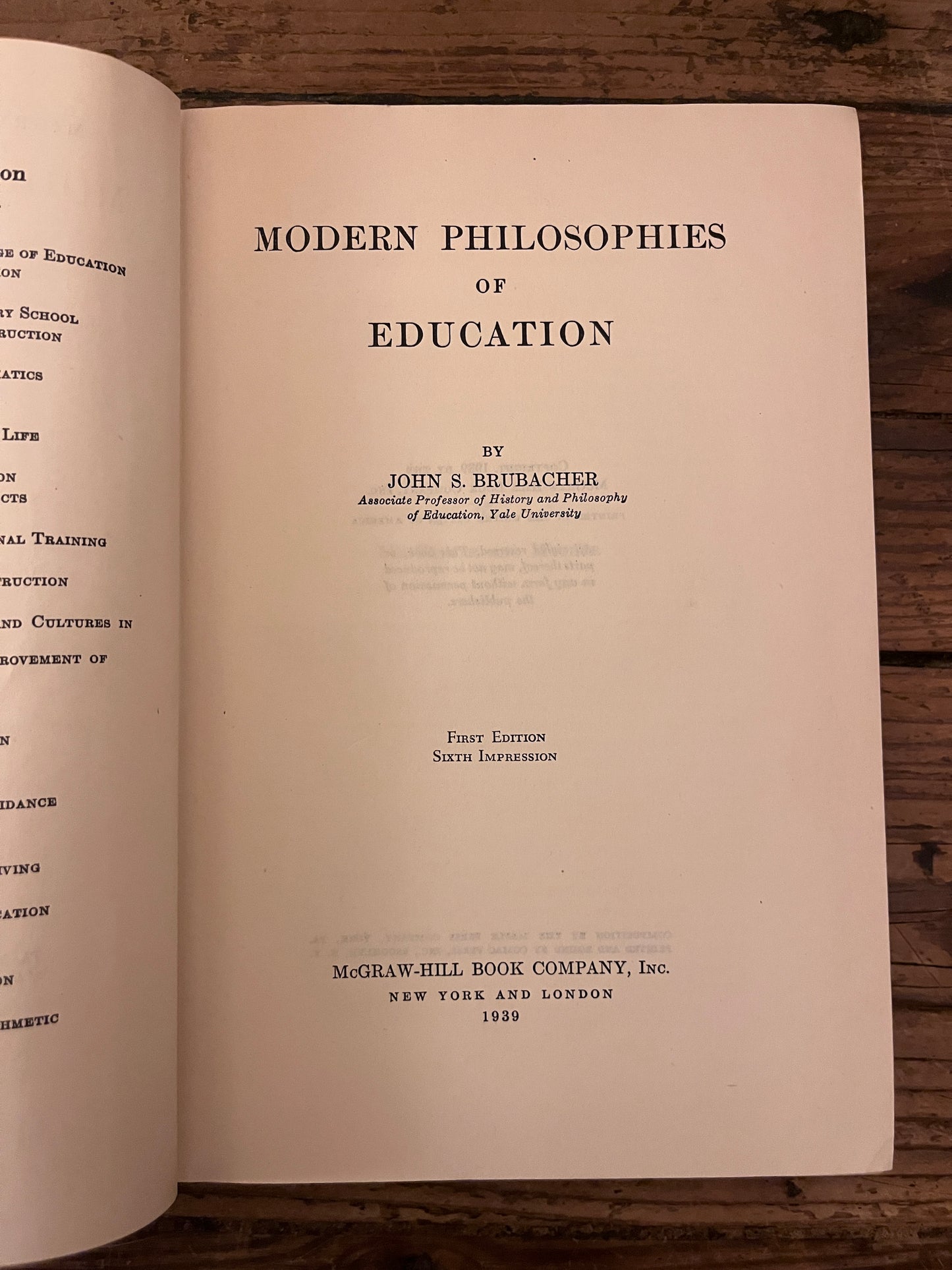 photo of the title page of the book "modern philosophies of educatio" on a wooden background
