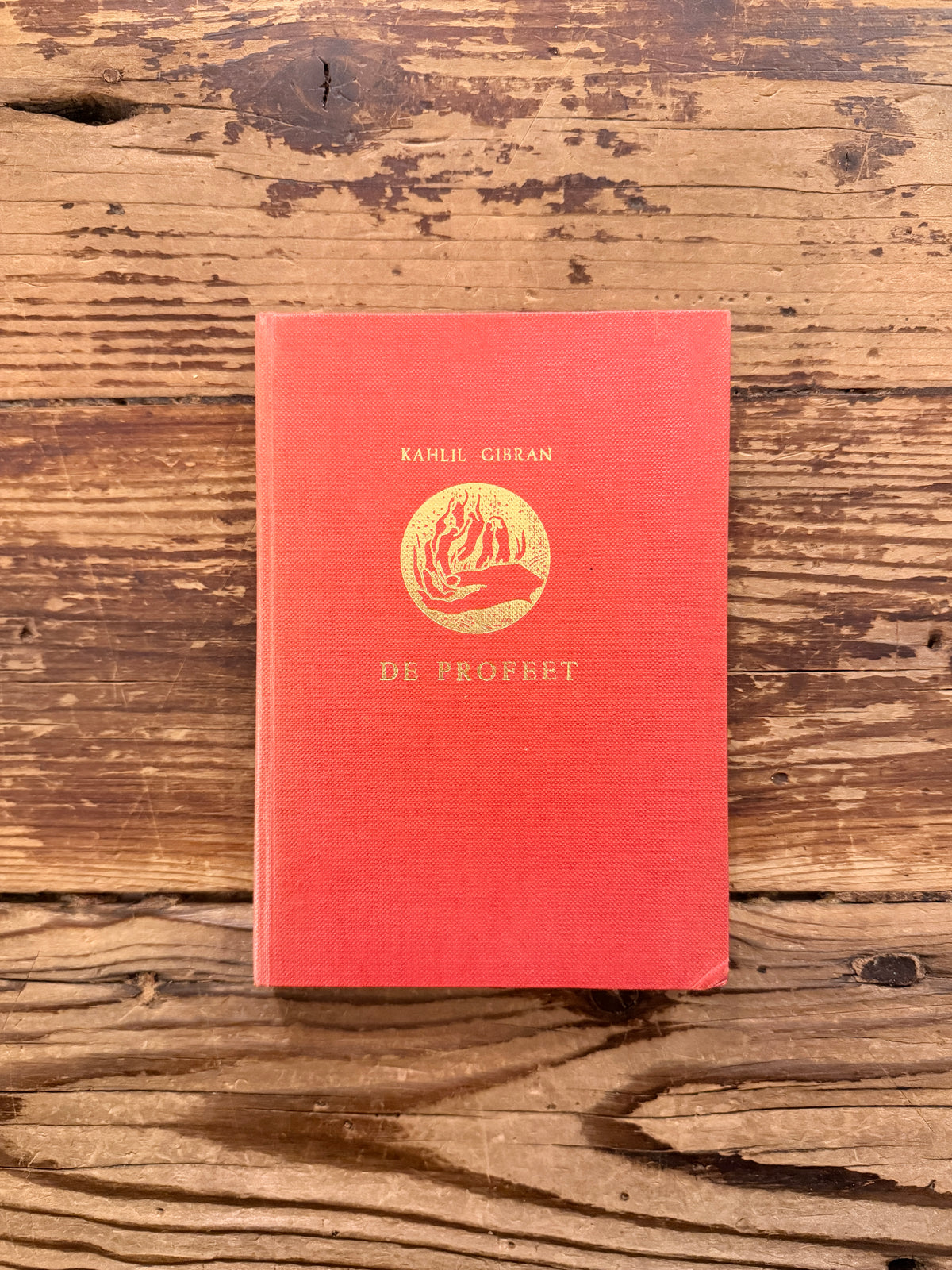 Voorkant van een boek met de titel 'De profeet' door Kahlil Gibran, op een houten  achtergrond 