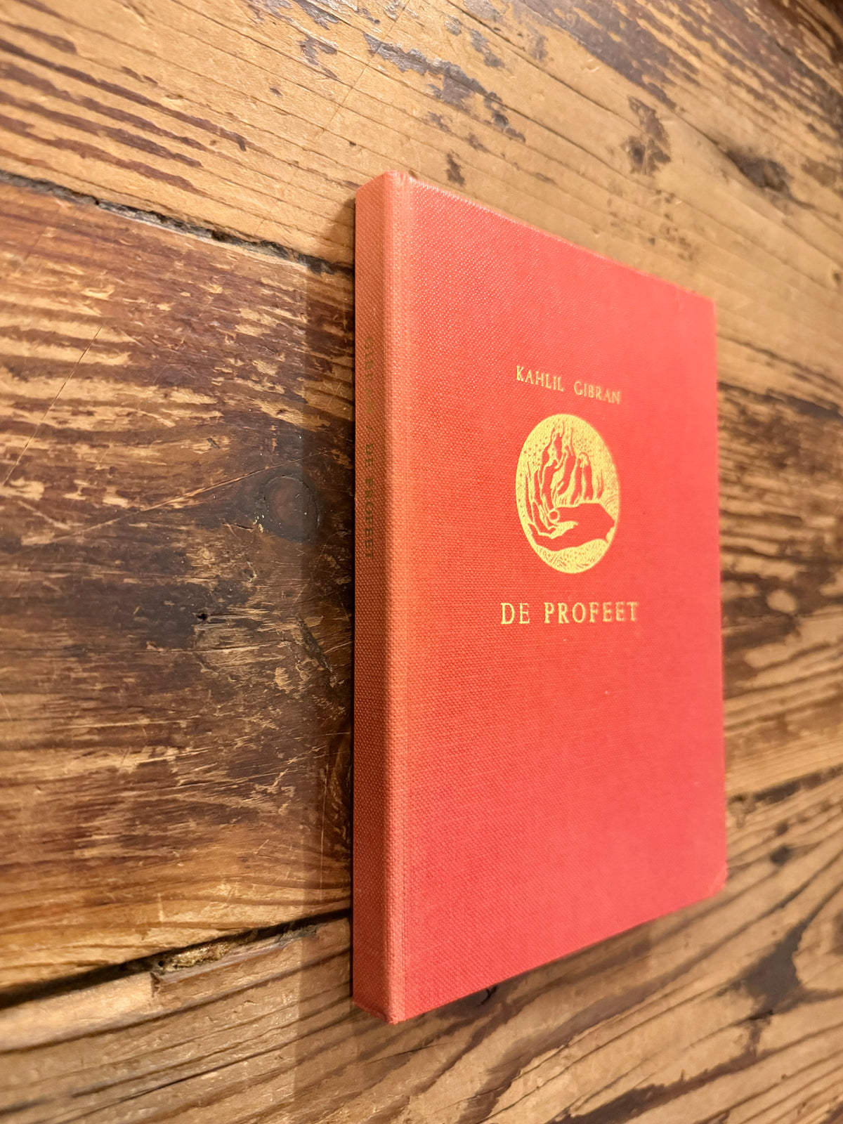Voorkant  en rug van een boek met de titel 'De profeet' door Kahlil Gibran, op een houten  achtergrond 