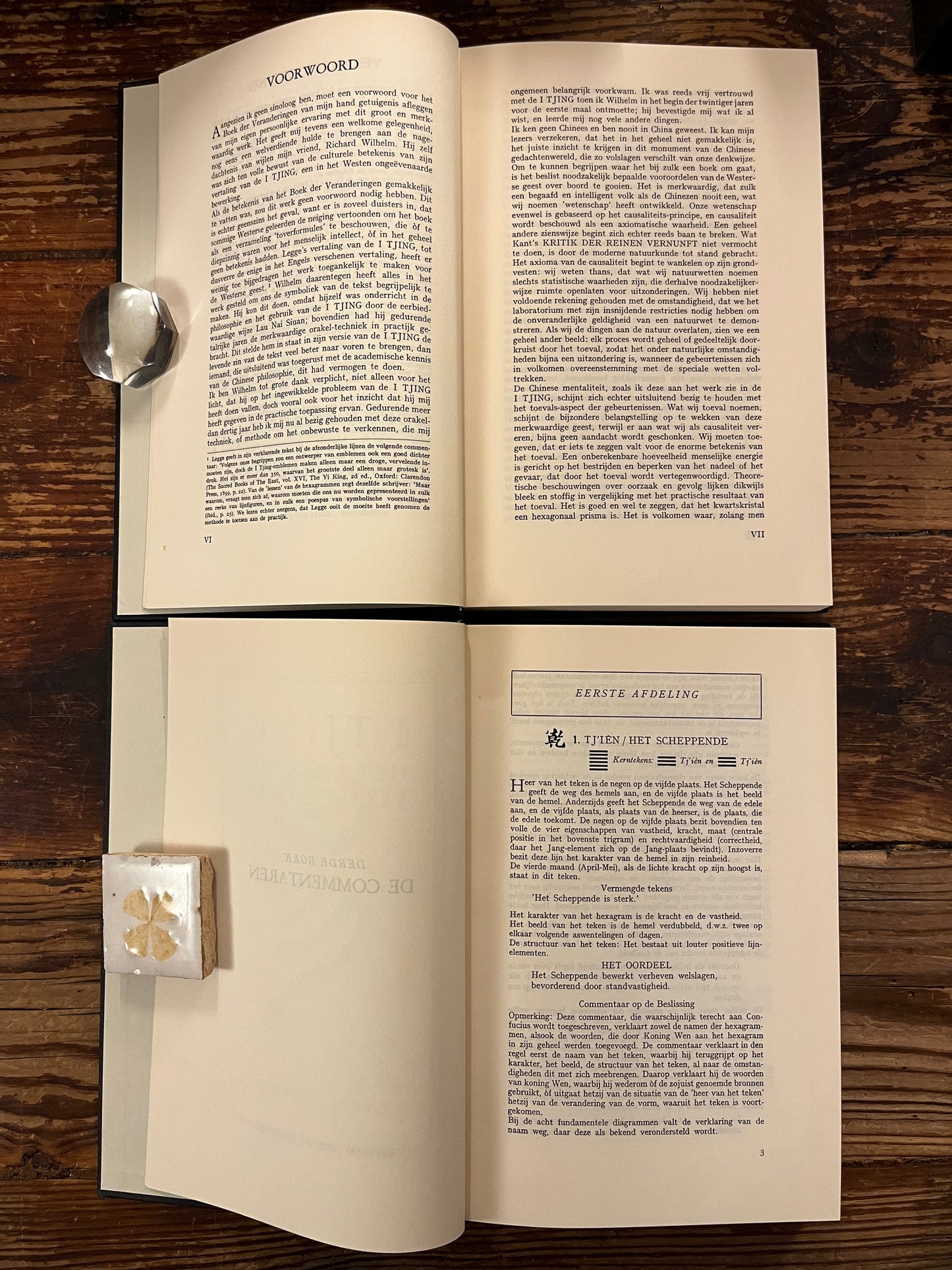 Twee open boeken met de titel 'I Tjing: Het Boek Der Veranderingen' op een houten achtergrond