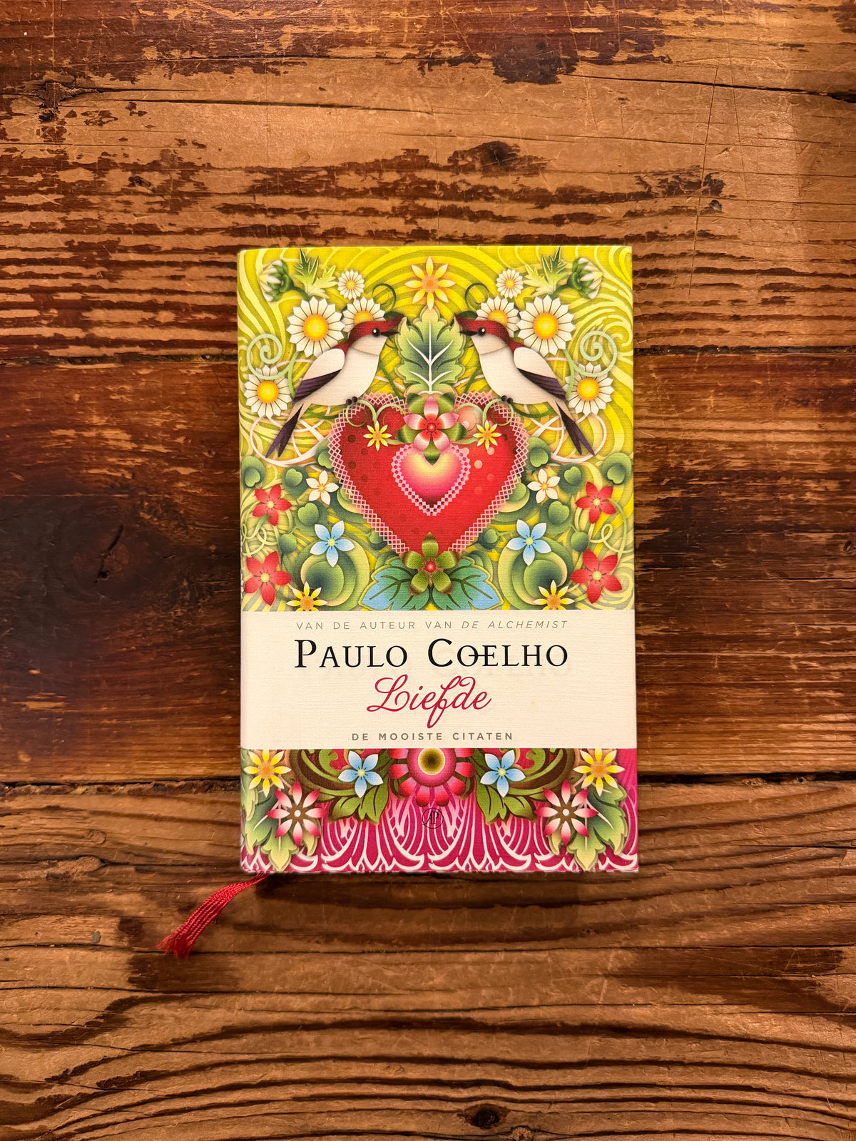 Voorkant van boek met de titel 'liefde' door Paulo Coelho op een houten achtergrond