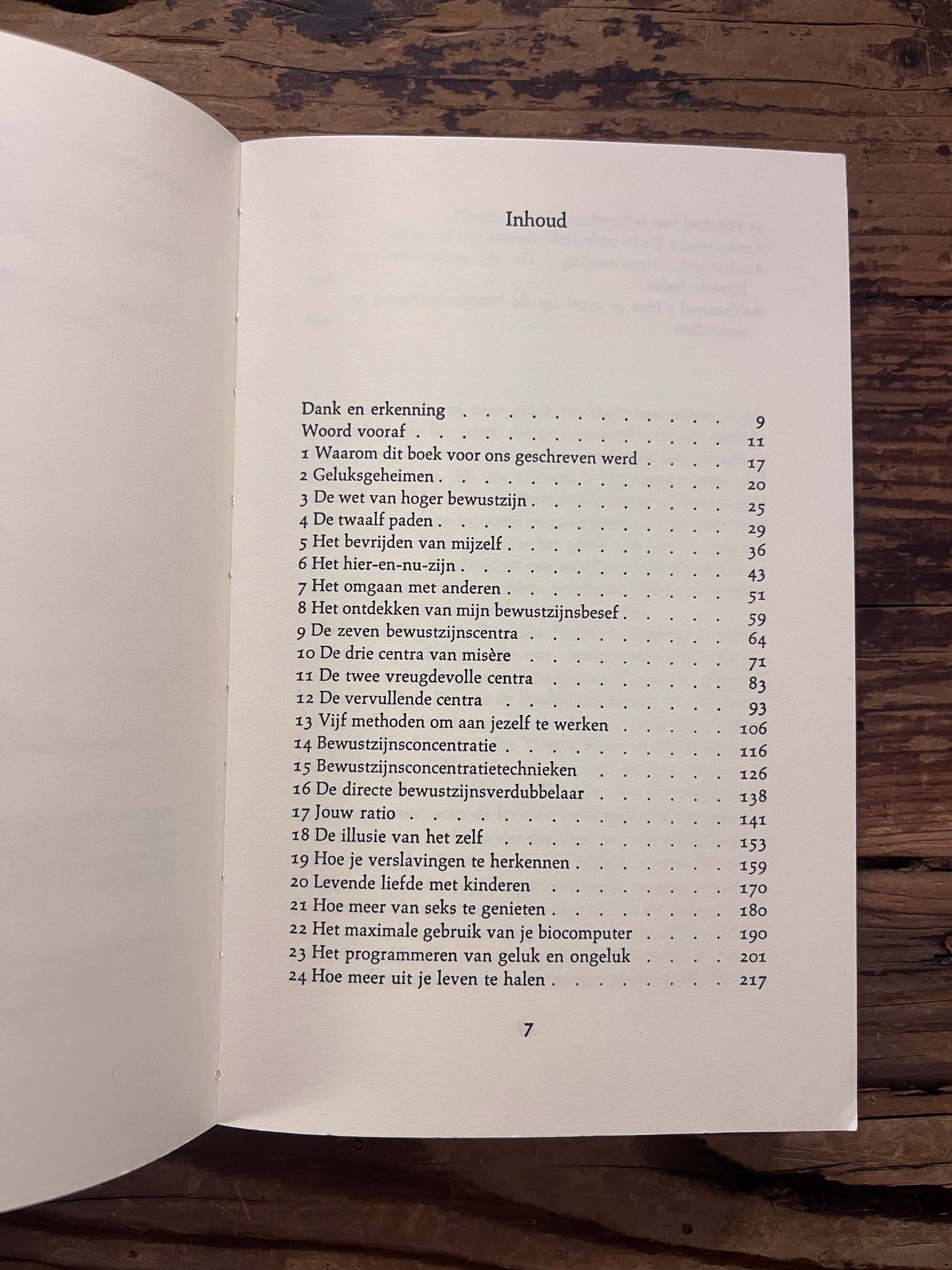 Inhoud van boek 'Handboek voor hoger bewustzijn' door Ken Keyes op een houten achtergrond 