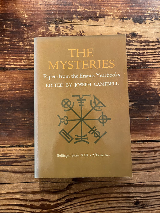 Book titled 'The Mysteries, papers from the Eranos Yearbooks' on a wooden surface