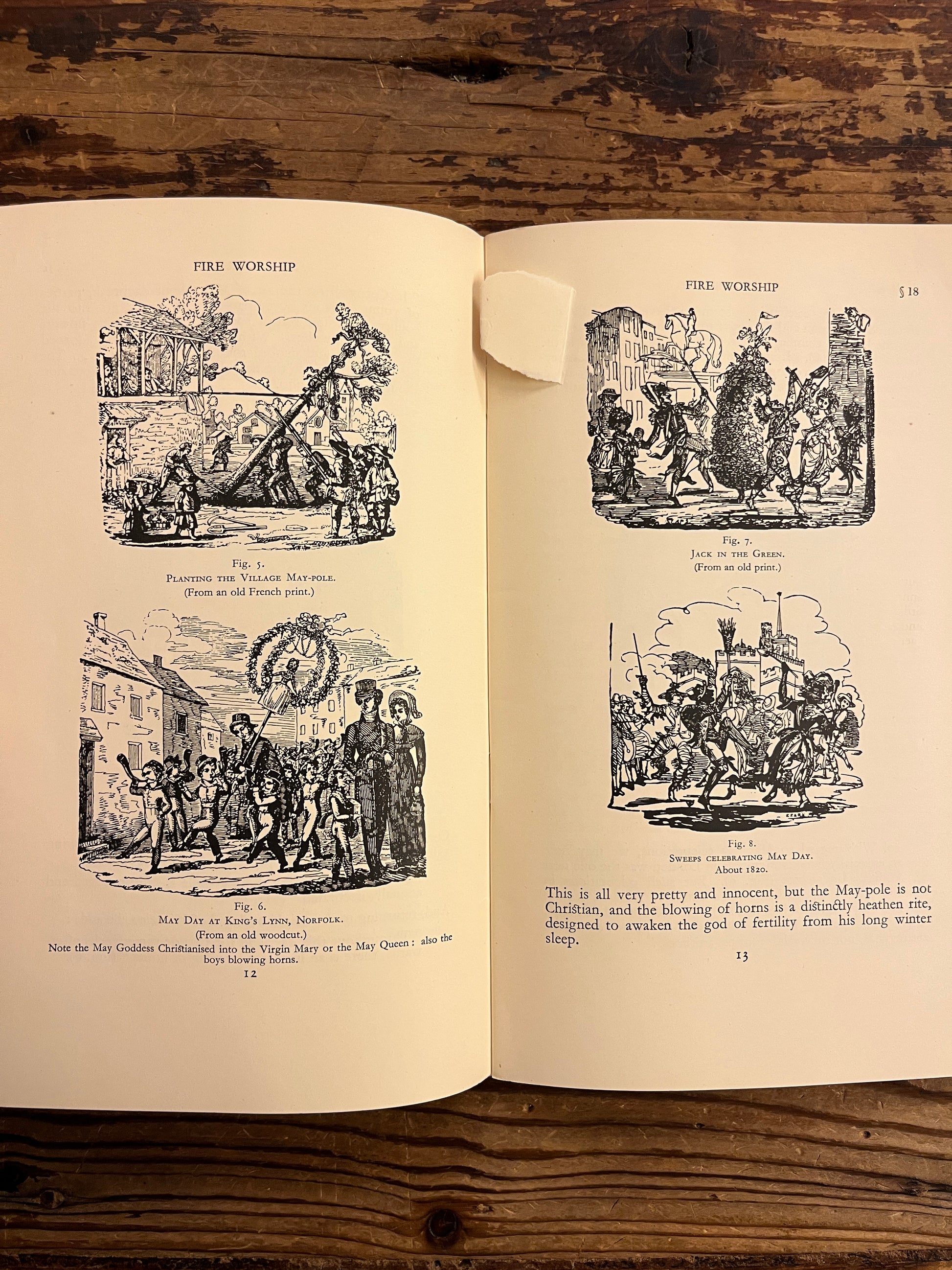 Open book with black and white illustrations on a wooden surface