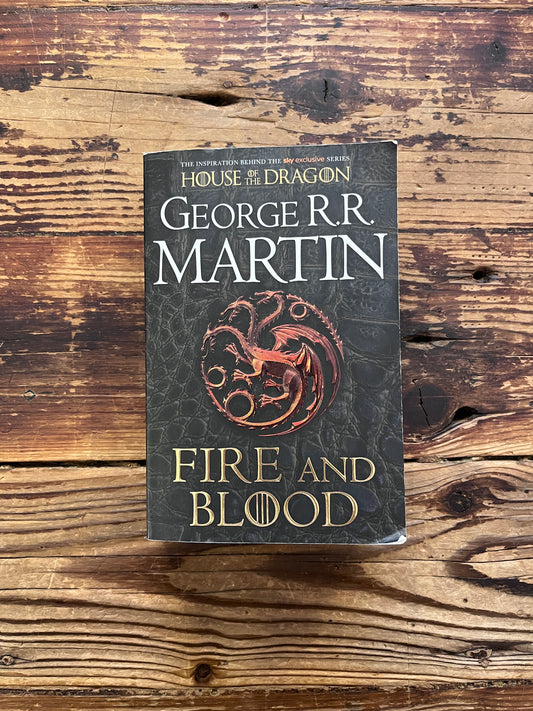 Book titled 'Fire and Blood' by George R.R. Martin on a wooden surface