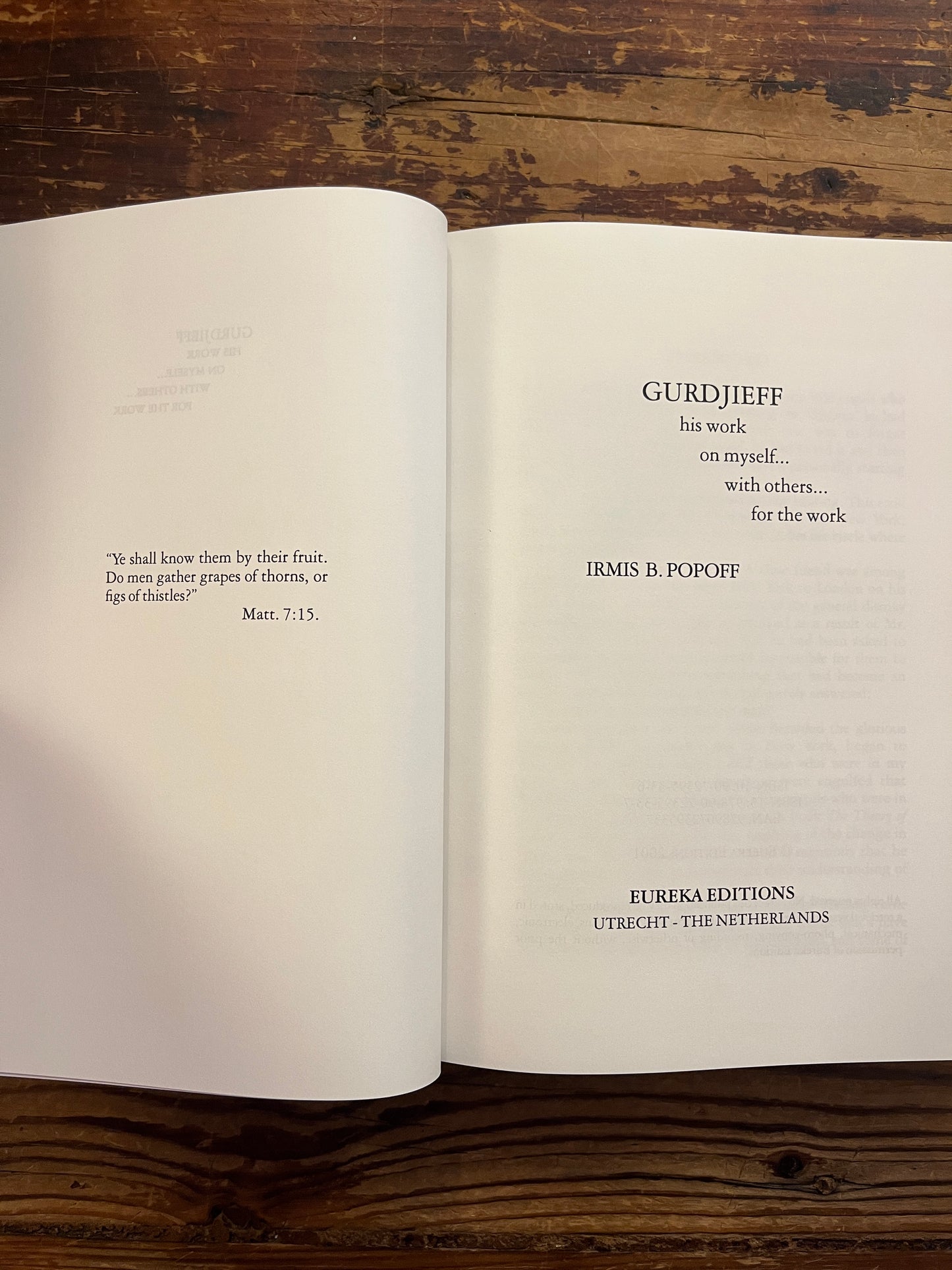 Open book titled 'Gurdjieff, His work, on myself, with others, for the work' by Irmis B. Popoff on a wooden surface