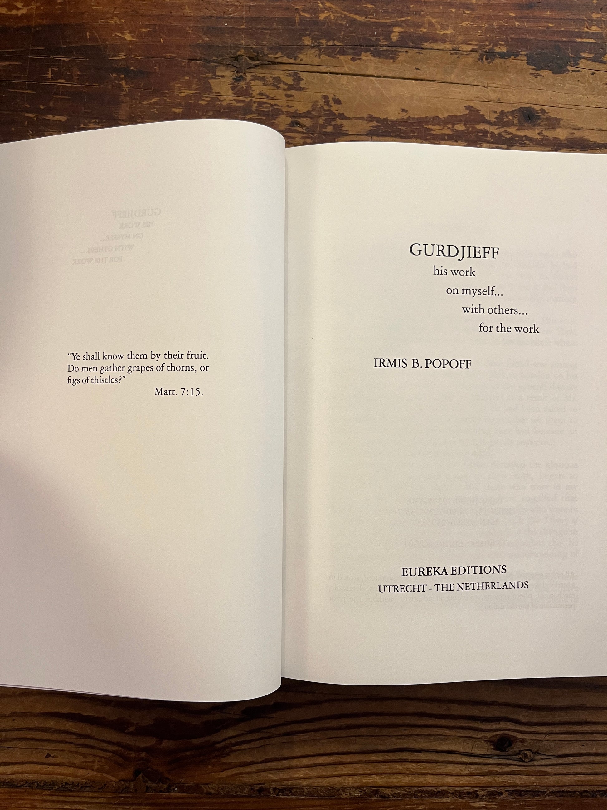 Open book titled 'Gurdjieff, His work, on myself, with others, for the work' by Irmis B. Popoff on a wooden surface