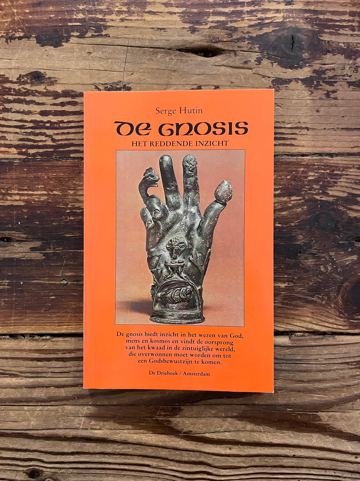 Voorkant van een boek met de titel 'De Gnosis' door Serge Hutin op een houten achtergrond 