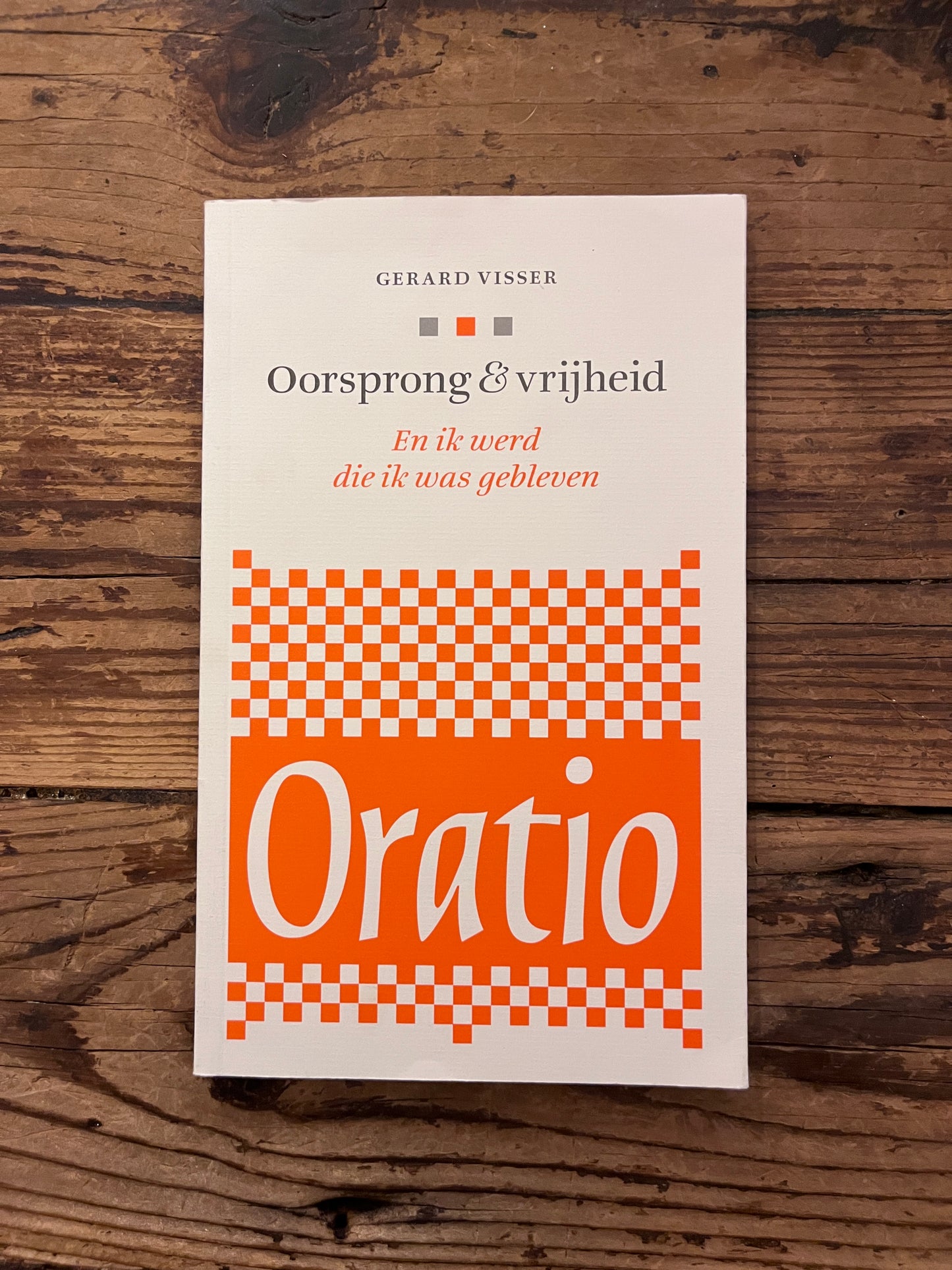 foto van de omslag van het boek "oorsprong en vrijheid" op houten achtergrond