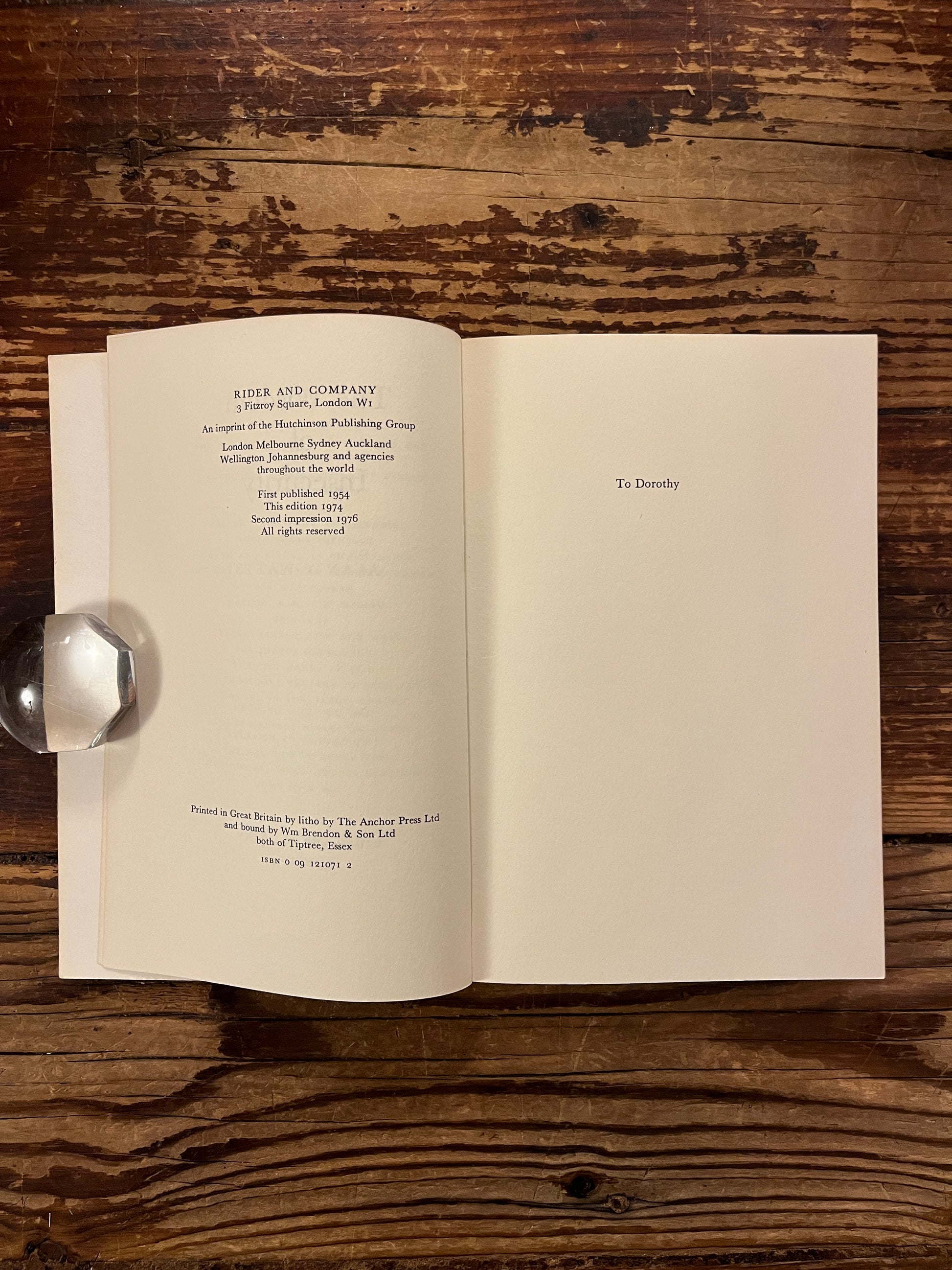 Open book with the title 'The Wisdom of Insecurity' by Alan W. Watts on a wooden surface