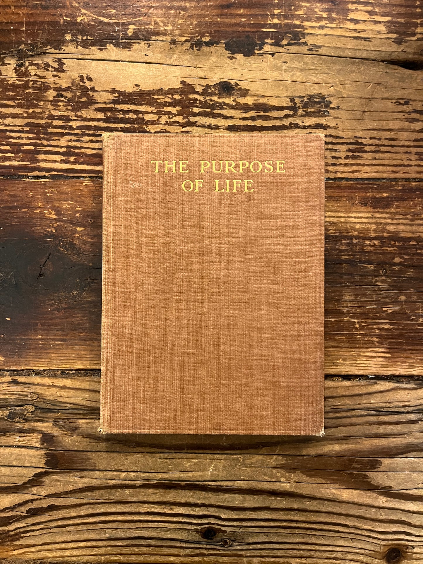 Front cover of book titled 'The Purpose of Life'  by Inayat Khan on a wooden surface