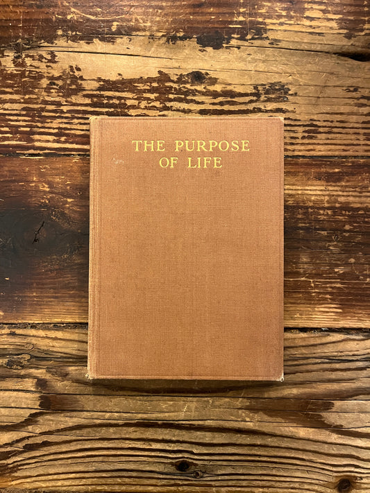 Front cover of book titled 'The Purpose of Life'  by Inayat Khan on a wooden surface