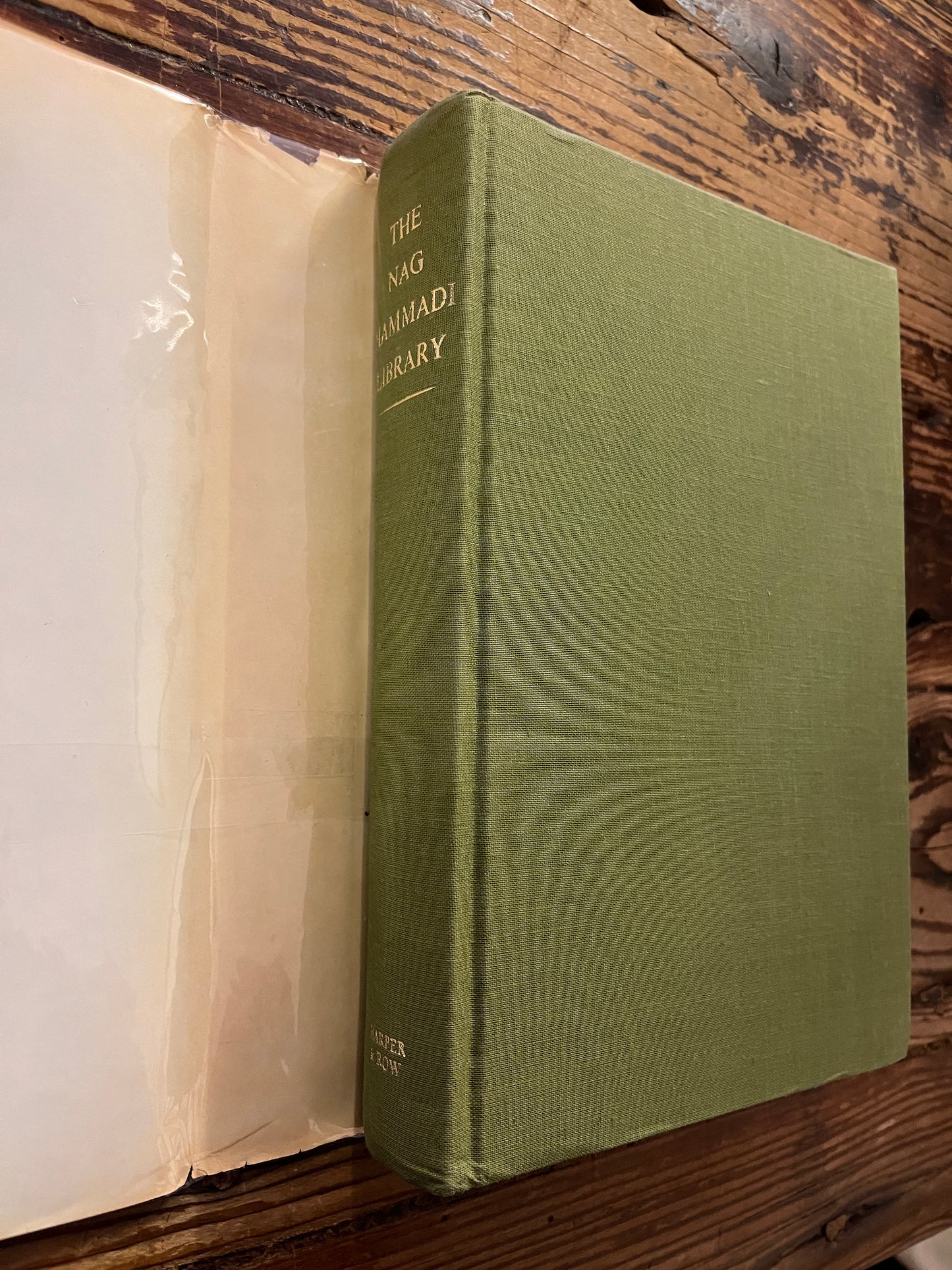 Book without dust-jacket titled 'The Nag Hammadi Library in English' on a wooden surface