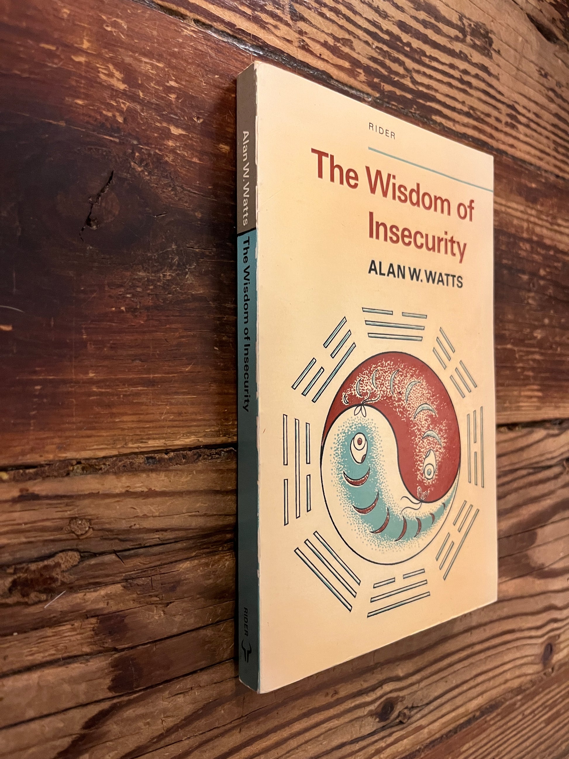 Spine of 'The Wisdom of Insecurity' by Alan W. Watts on a wooden surface