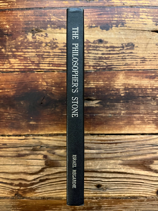 Spine of book 'the philosopher's stone' by Israel Regardie on a wooden surface 