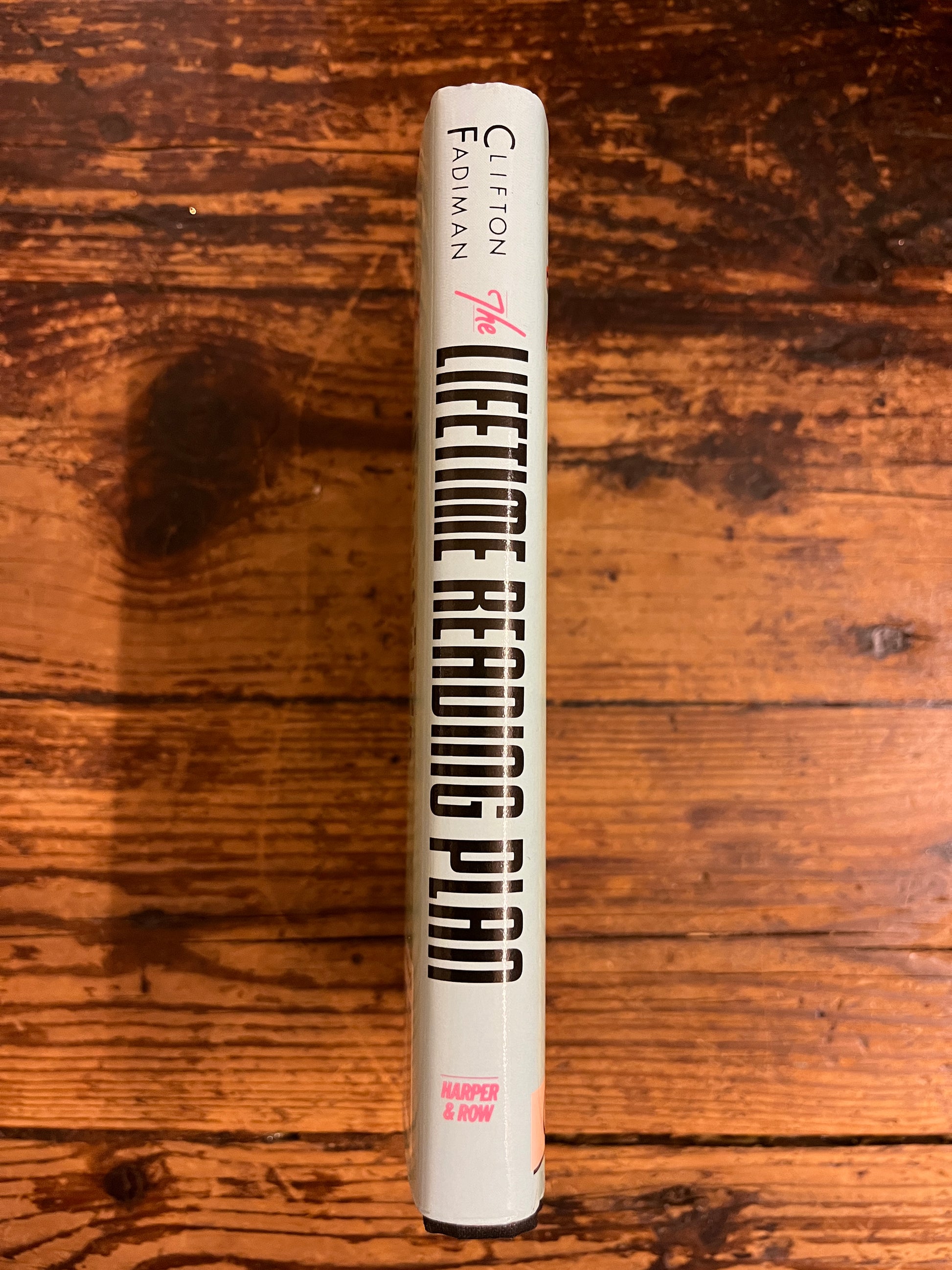 spine of the book "the lifetime reading plan"on a wooden background