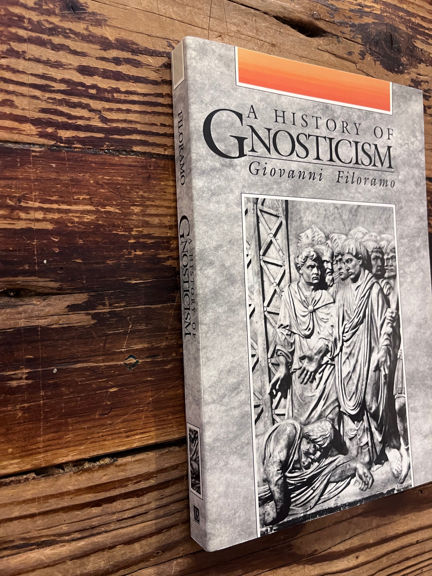 Front cover a spine of a book titled 'A History of Gnosticism' by Giovanni Filoramo on a wooden surface