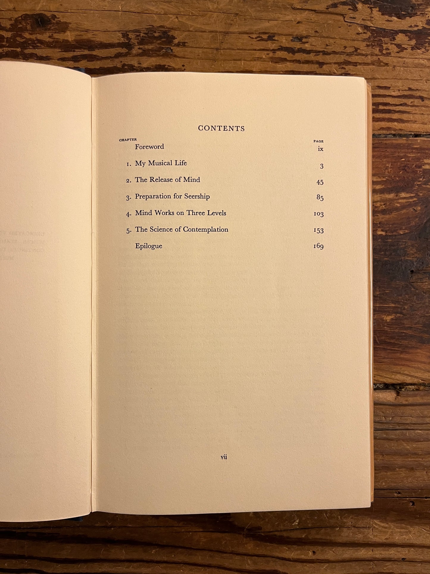 Open book showing the contents of book 'three levels of consciousness' by Minnie B. Theobald on a wooden surface 