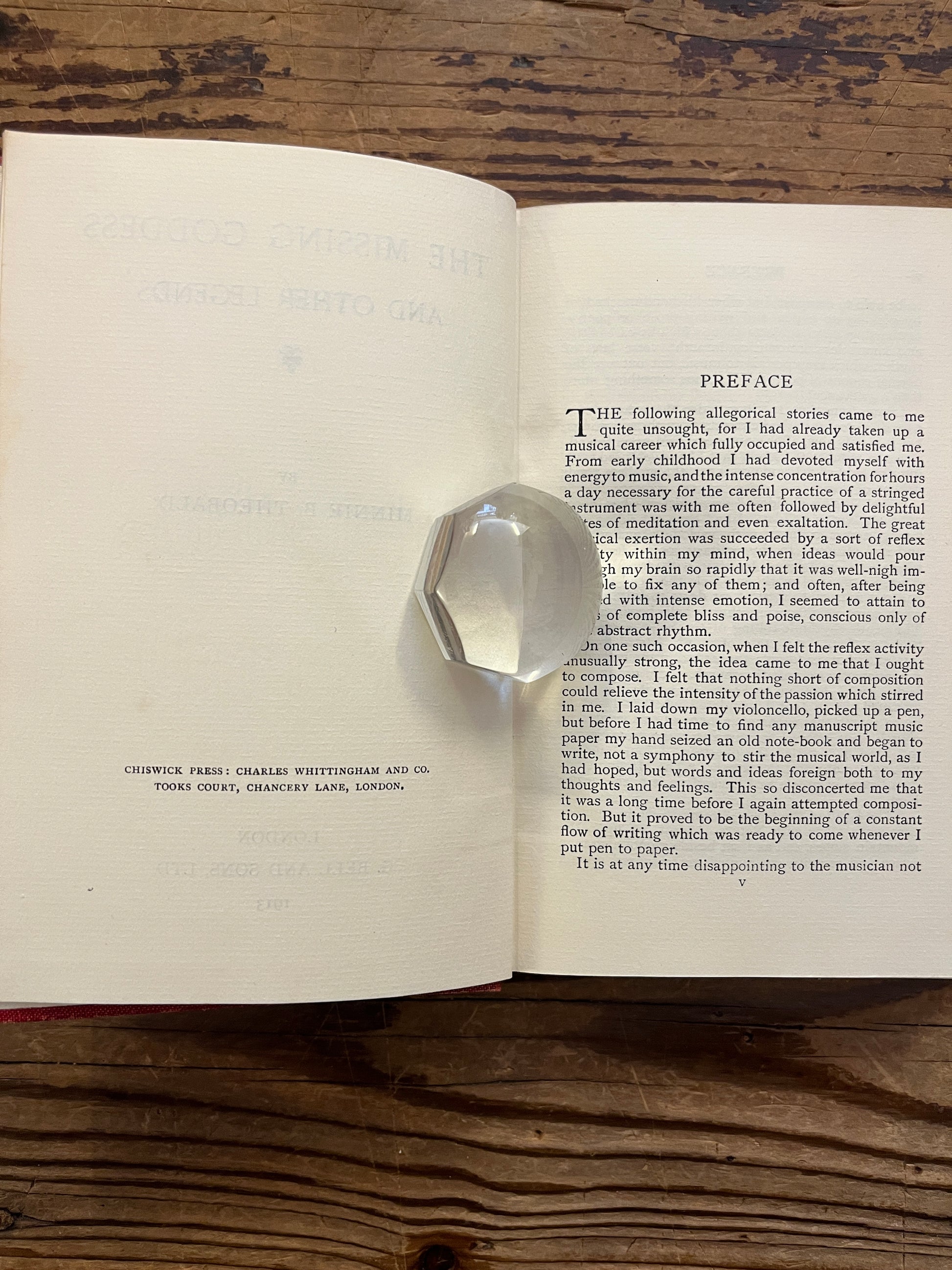 Open book titled 'the missing Goddess and other legends' by Minnie Theobald on a wooden surface