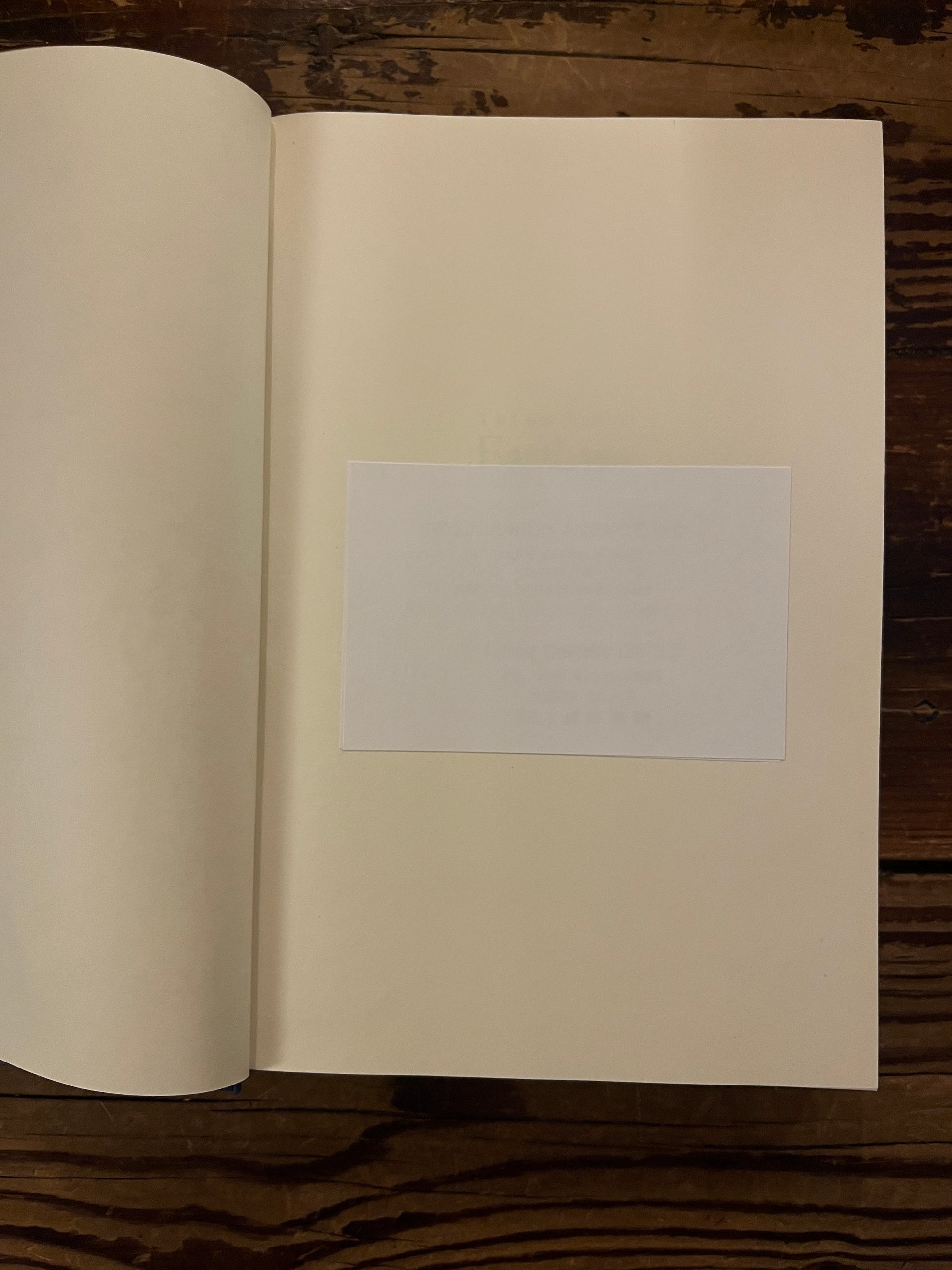 Open book showing a white sticker in a book titled 'Tales from Earthsea' by Ursula K. Le Guin on a wooden surface