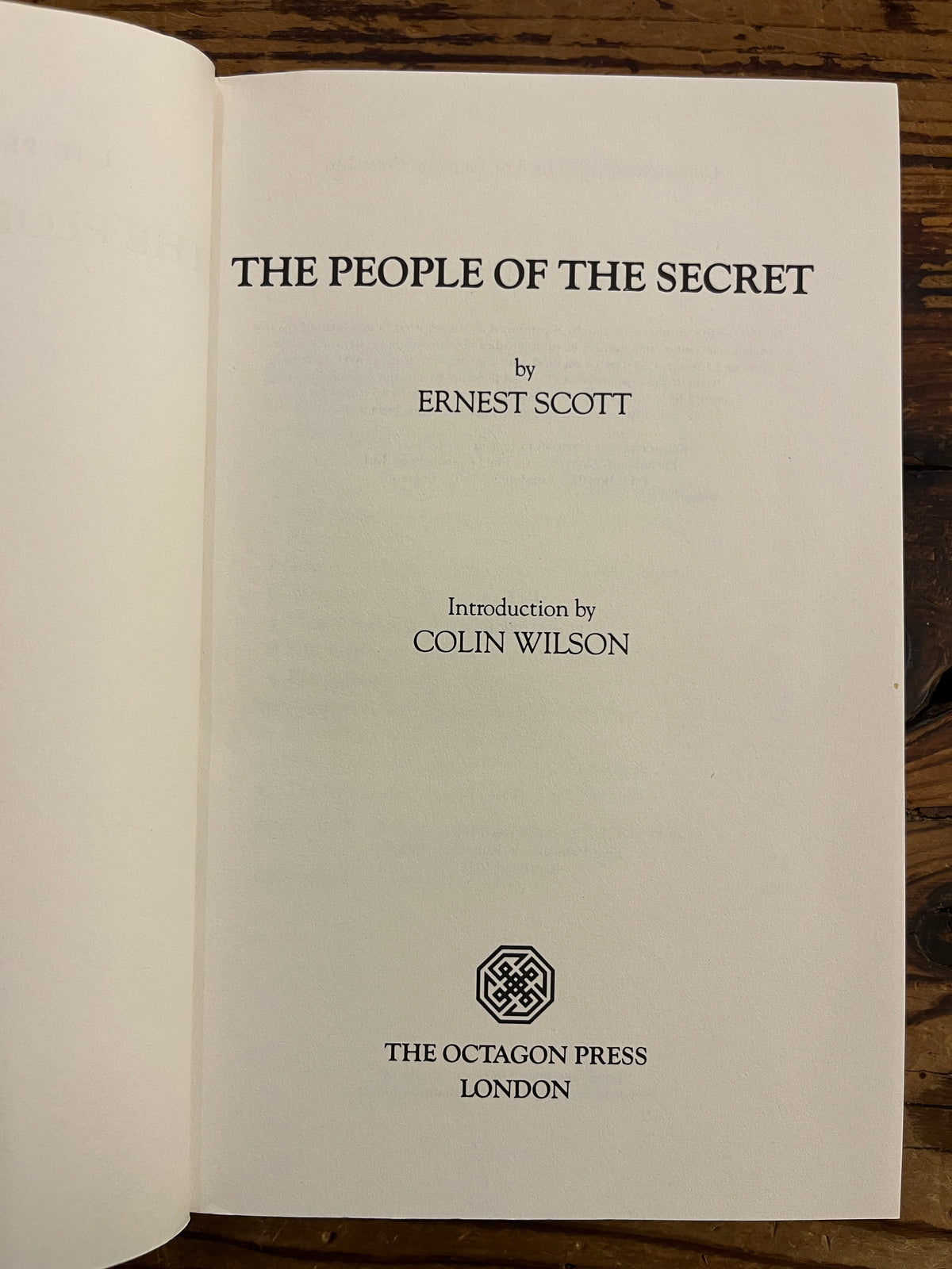 First page of book with the title 'The People of the Secret' by Ernest Scott lying on a wooden surface