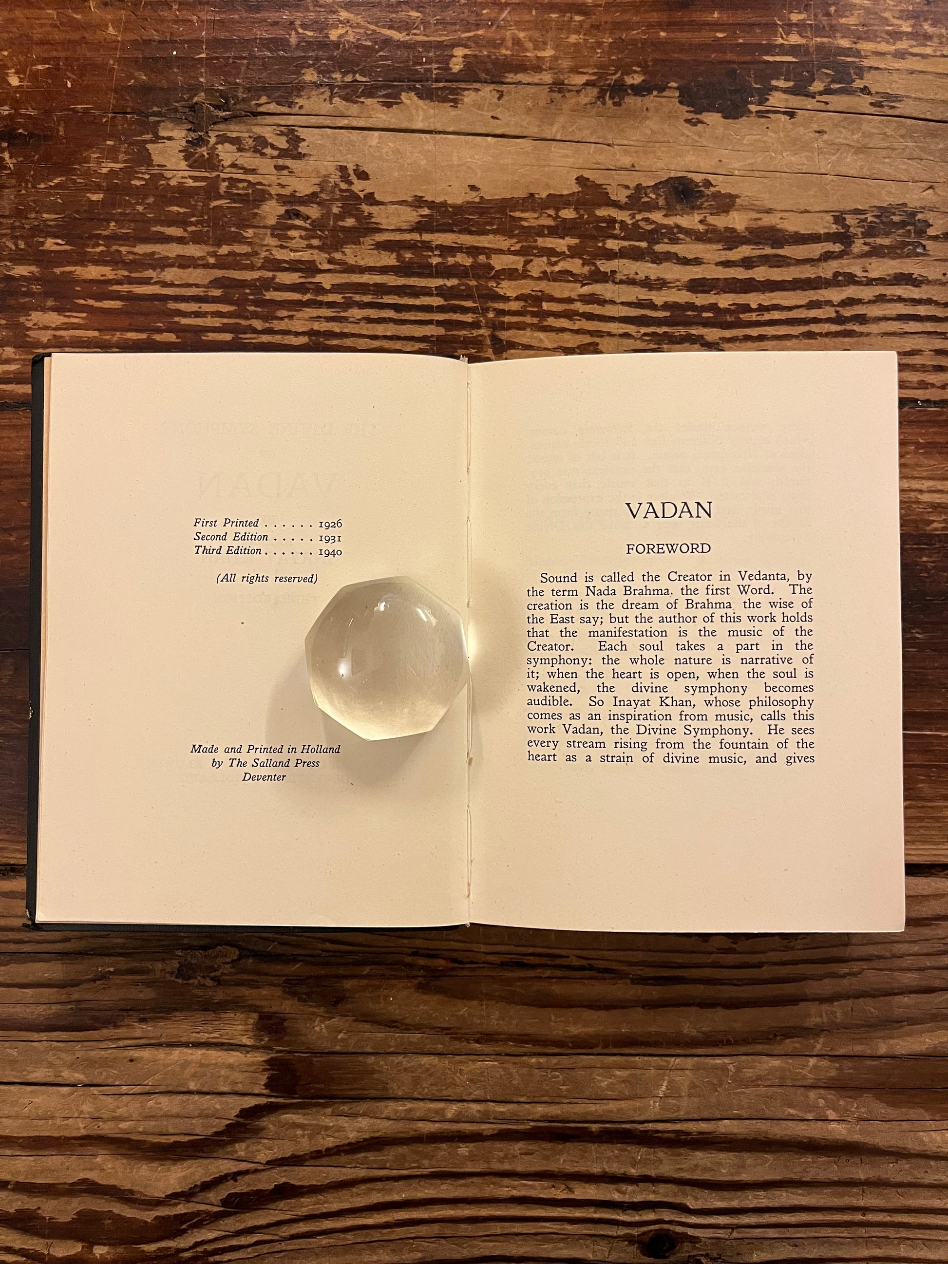 Open book titled 'The divine symphony or Vadan'  by Hazrat Inayat Khan on a wooden surface 