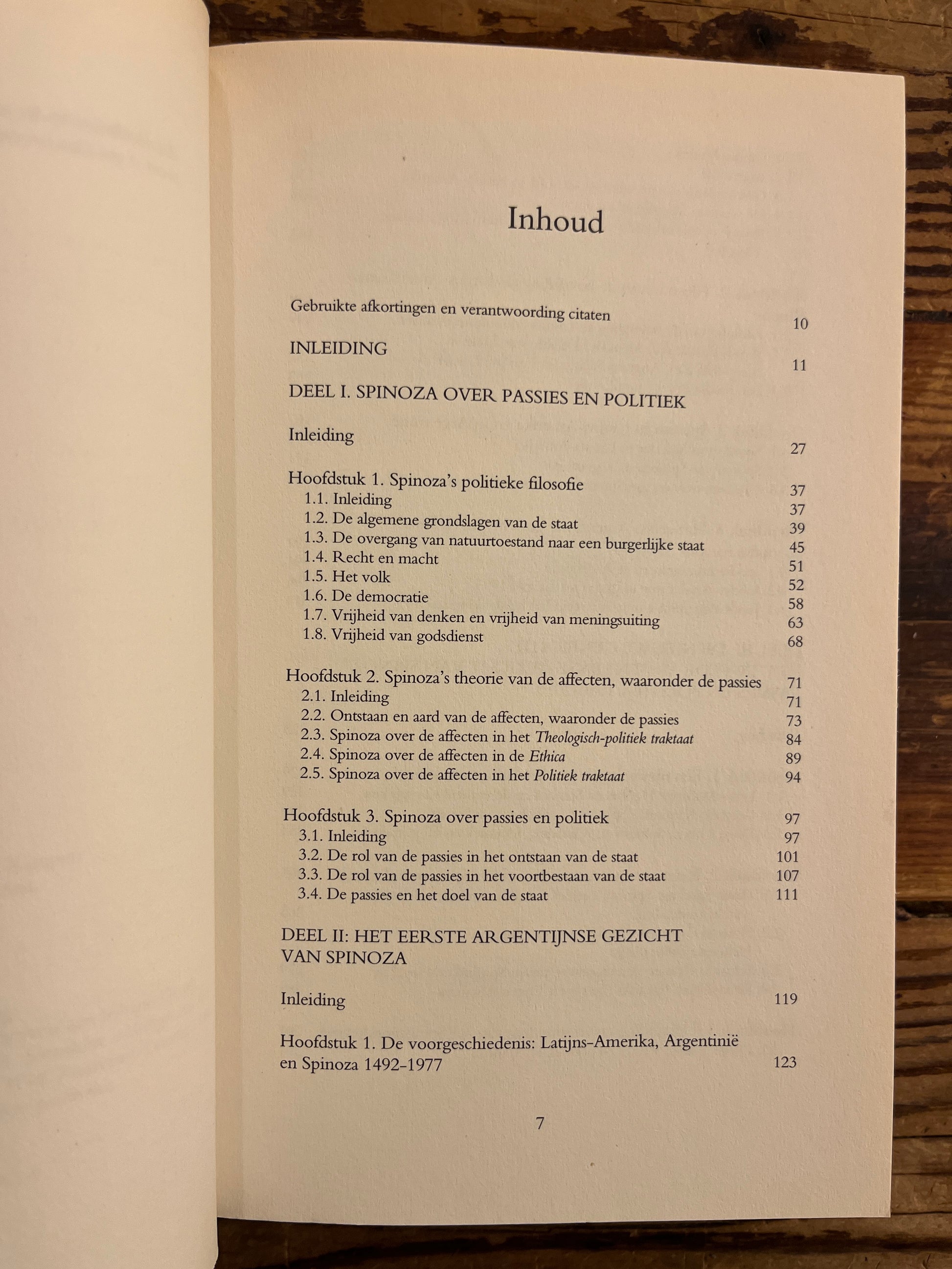 Open boek met de titel 'het Argentijnse gezicht van Spinoza' door Miriam van Reijen op een houten achtergrond 