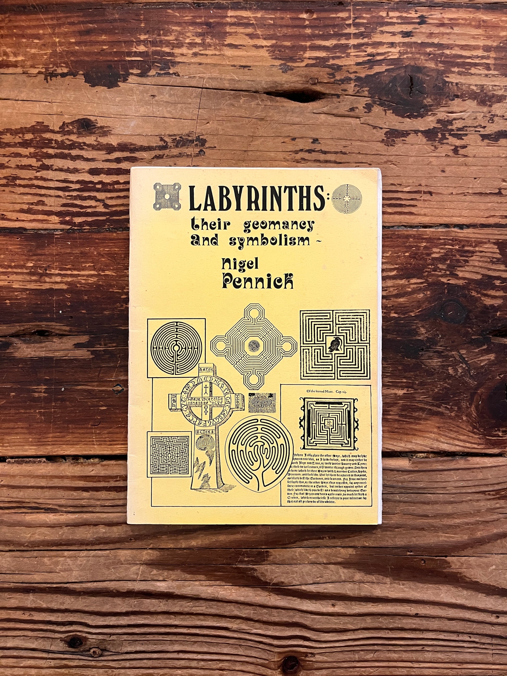 Front cover of booklet with the title 'Labyrinths, their geomancy and symbolism' by Nigel Pennick on a wooden surface 