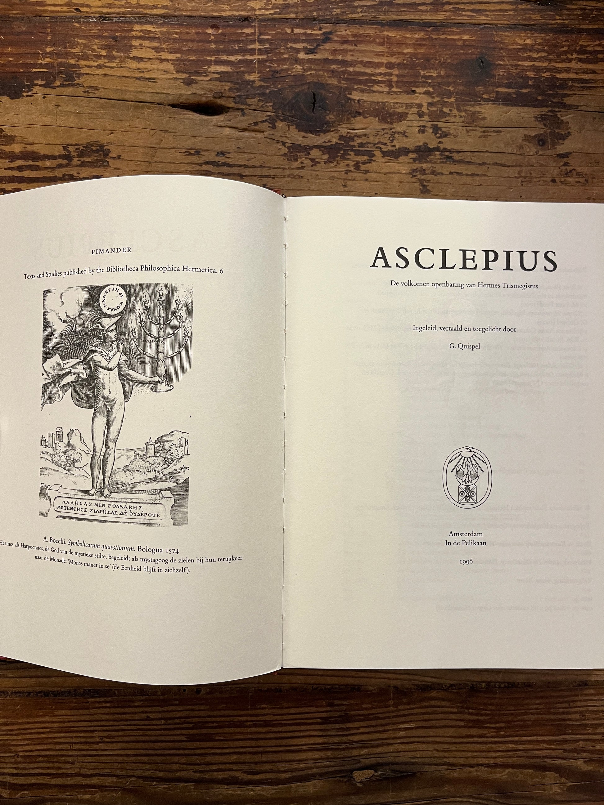 Open boek met de titel 'Asclepius' ingeleid, vertaald en toegelicht door G. Quispel op een houten achtergrond 