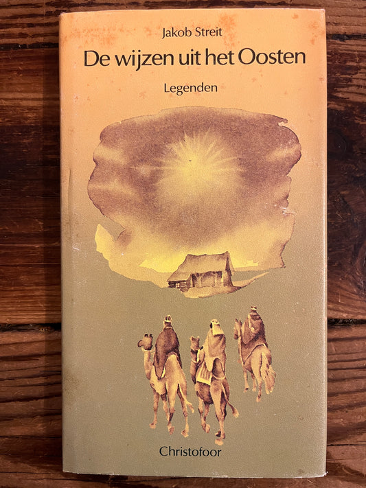 Voorkant met stof omslag van boek met de titel 'De wijzen uit het Oosten' door Jakob Streit op een houten achtergrond 