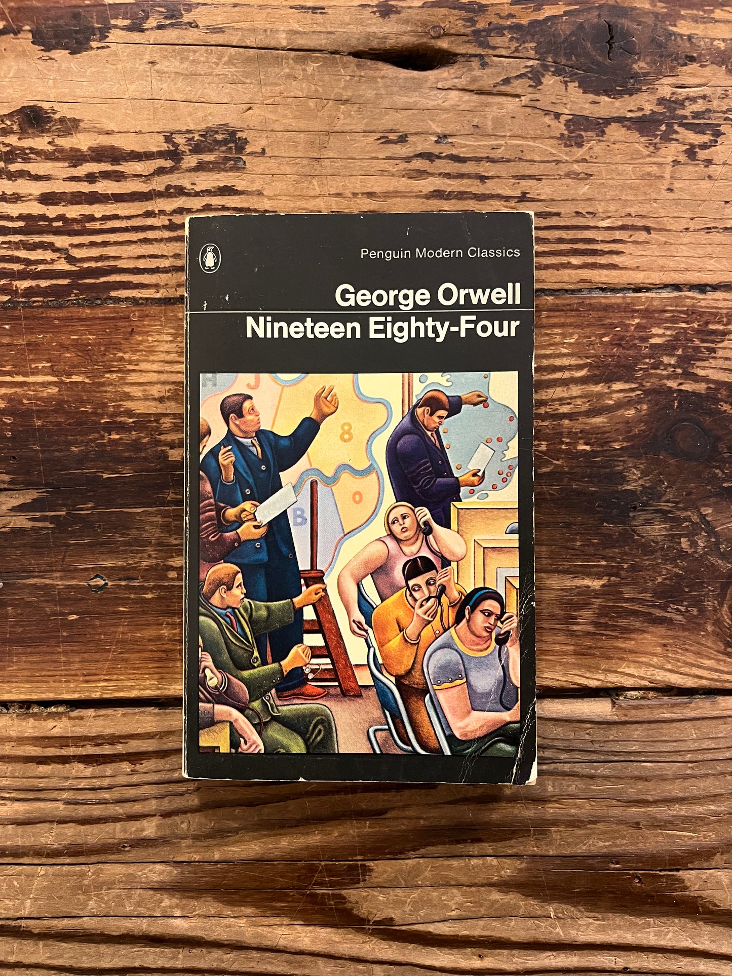Front cover  book titled 'Nineteen Eighty-Four' by George Orwell on a wooden surface