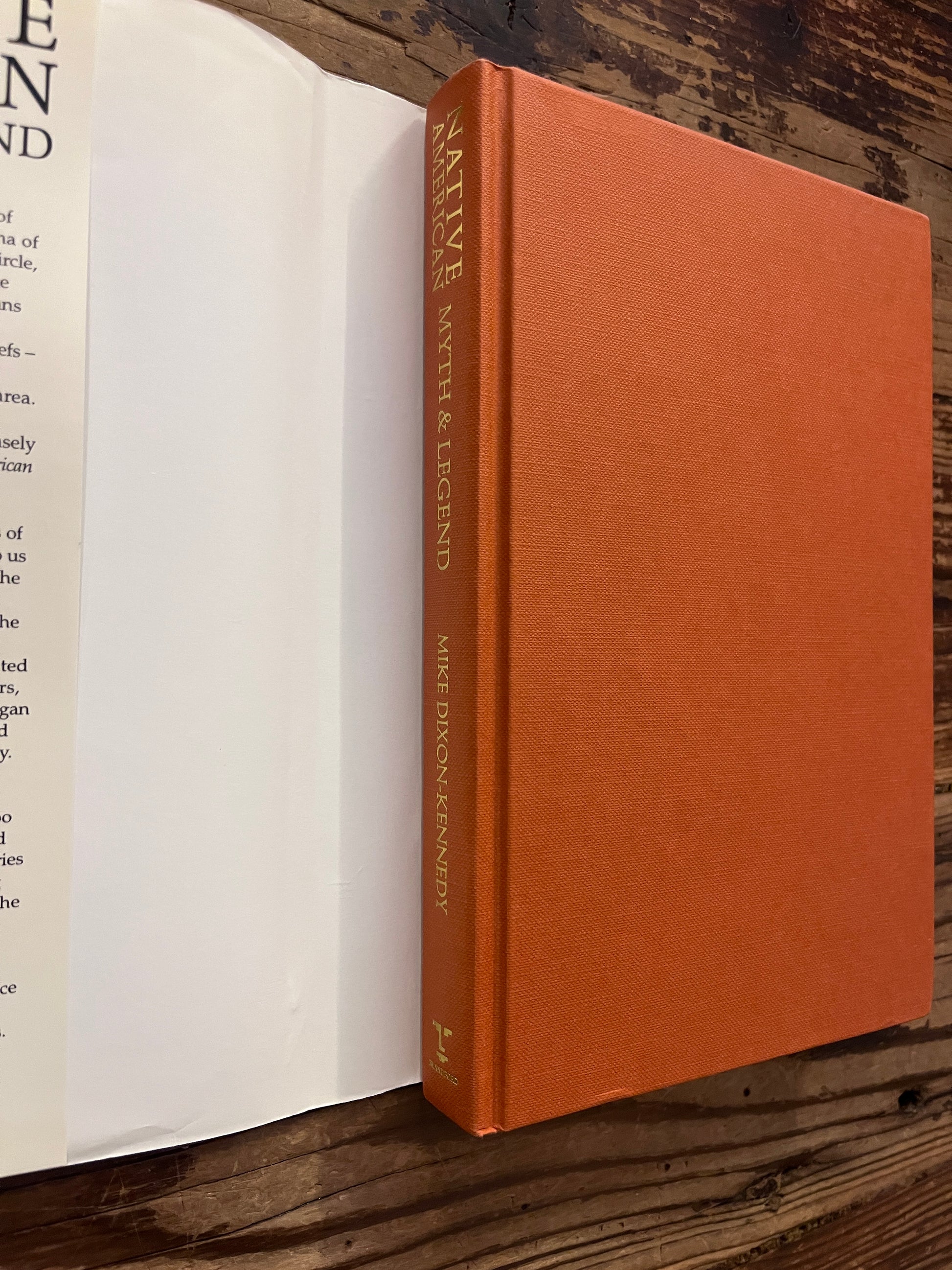 Open book without dust jacket titled 'Native American Myth & Legend' by Mike Dixon-Kennedy on a wooden surface