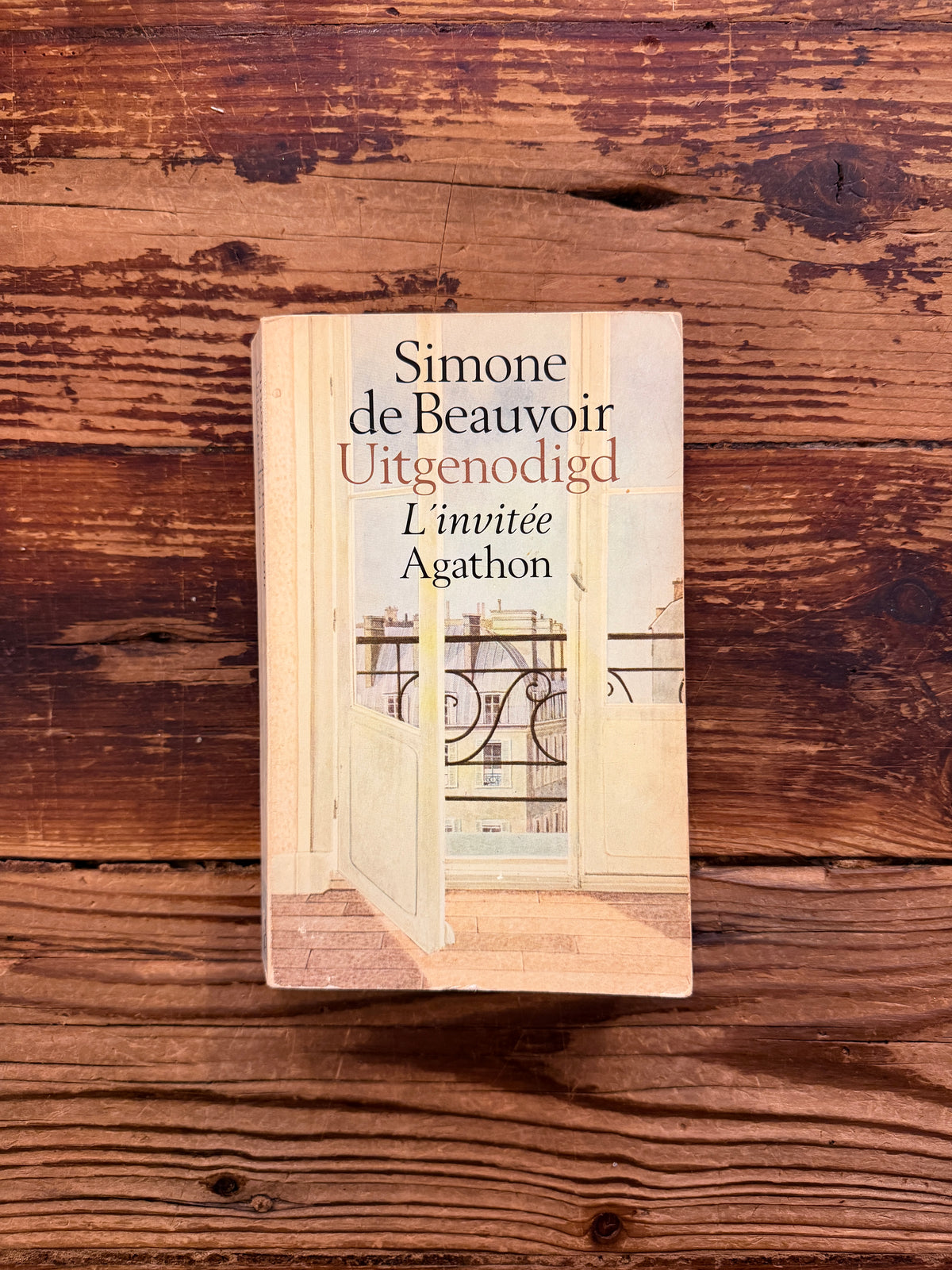 voorkant van boek met de titel 'Uitgenodigd, l'invitée' door Simone de Beauvoir op een houten achtergrond