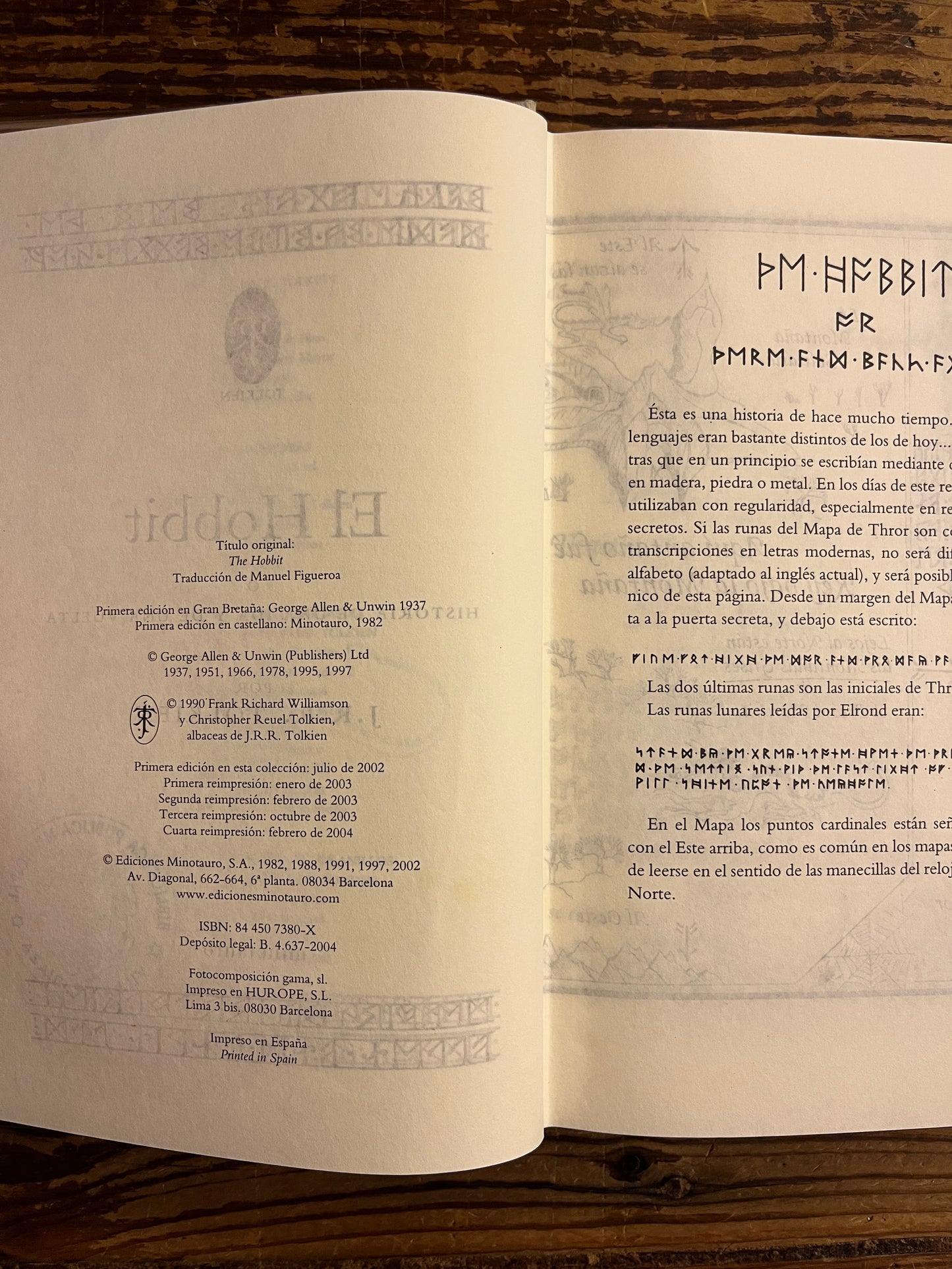 Open book titled 'The Hobbit' by J.R.R. Tolkien on a wooden surface