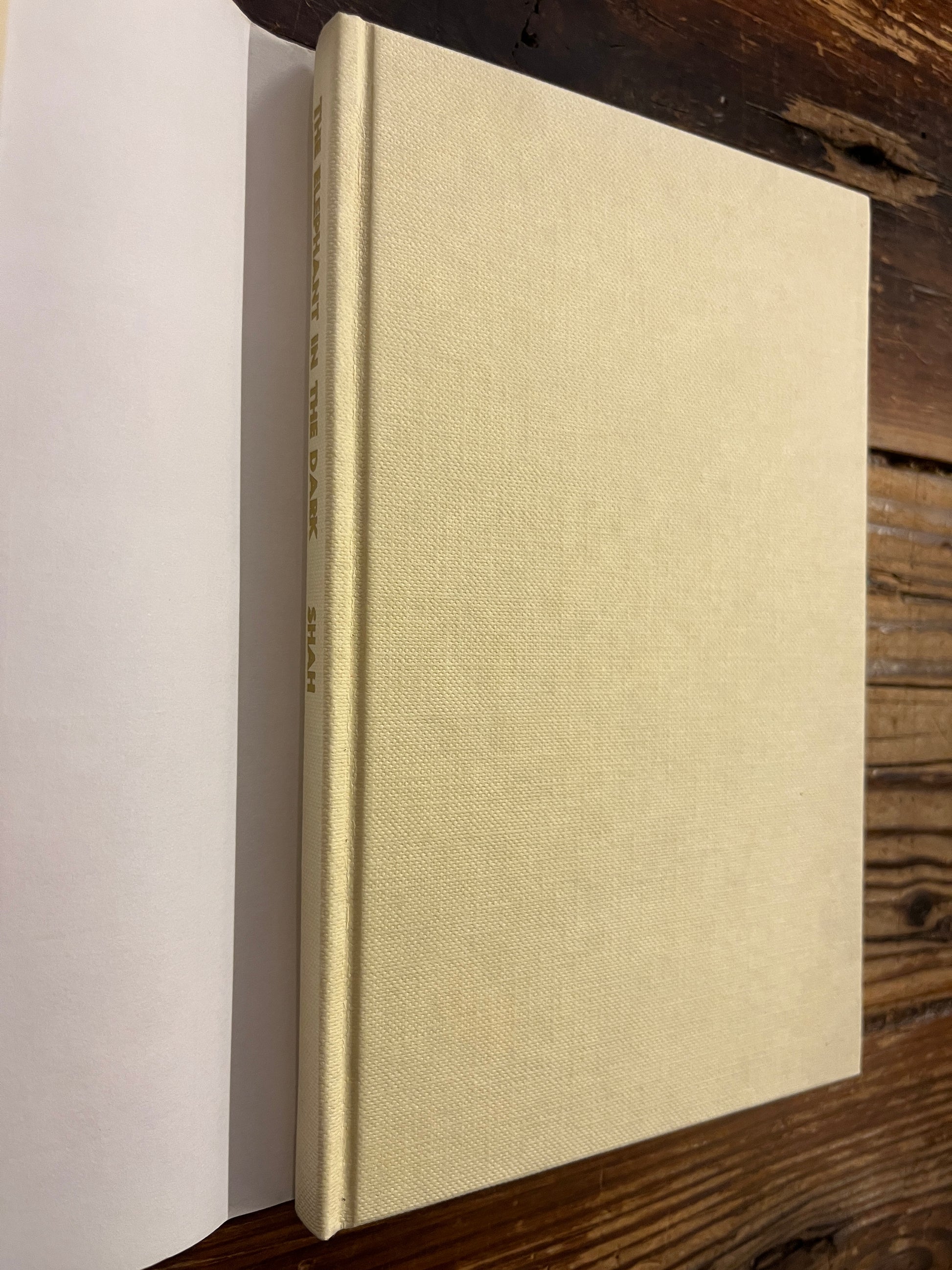 Beige book titled 'the elephant in the dark' by Idries Shahon a wooden surface