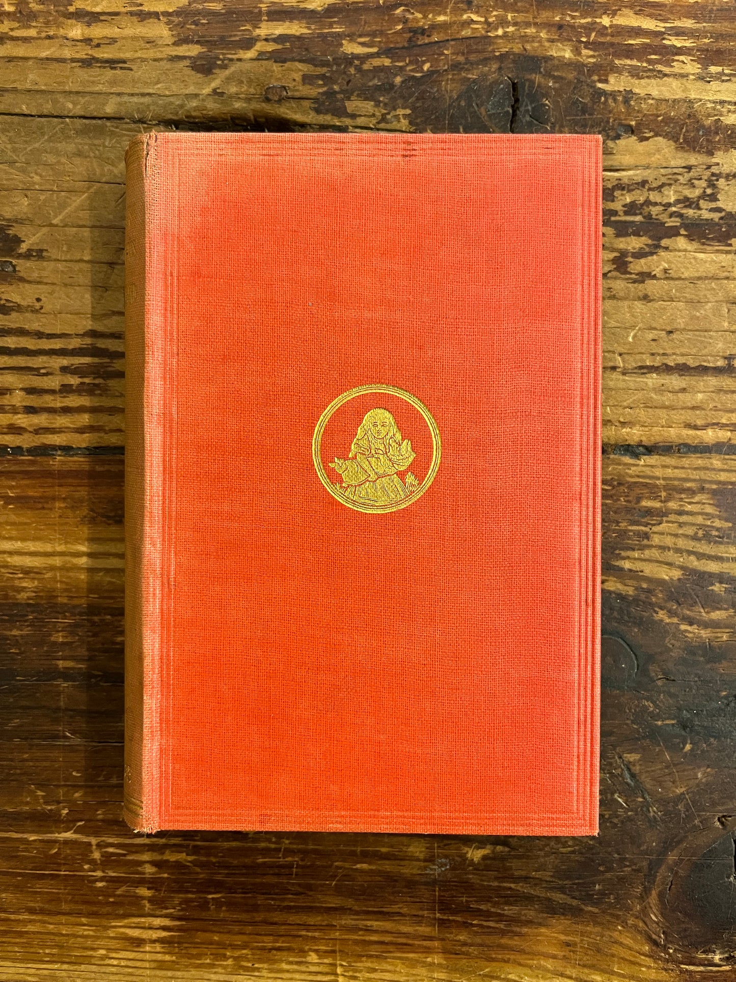 front cover of a 1922 macmillan & co miniature edition of 'Alice's adventures in wonderland' by Lewis Carroll on a wooden surface