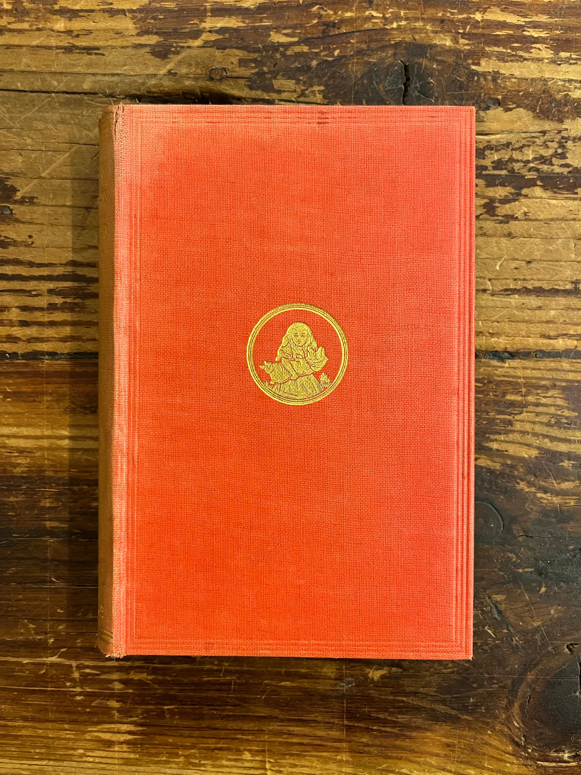 front cover of a 1922 macmillan & co miniature edition of 'Alice's adventures in wonderland' by Lewis Carroll on a wooden surface