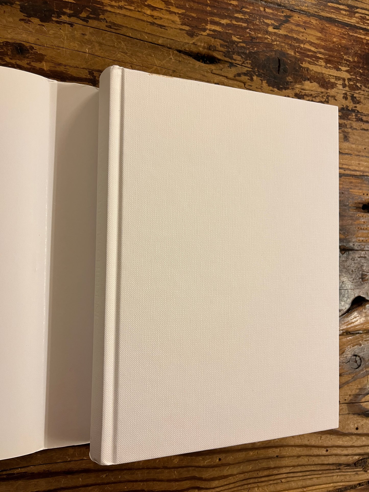 boek met de titel 'De Geschiedenis Van Imaginaire Landen En Plaatsen' door Umberto Eco zonder stof omslag op een houten achtergrond 