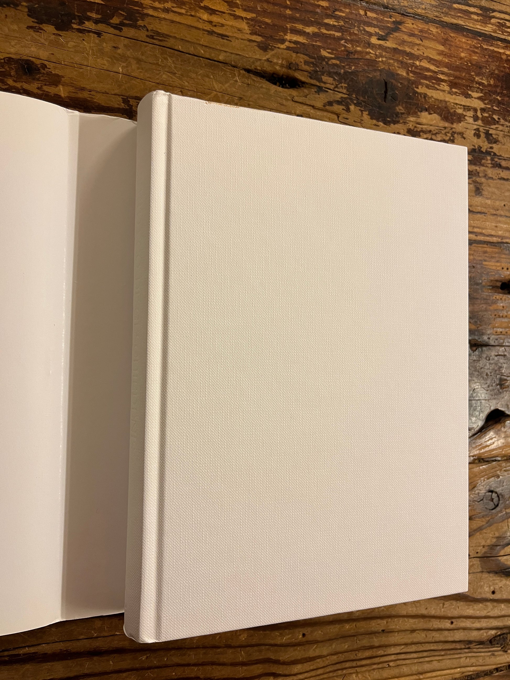 boek met de titel 'De Geschiedenis Van Imaginaire Landen En Plaatsen' door Umberto Eco zonder stof omslag op een houten achtergrond 