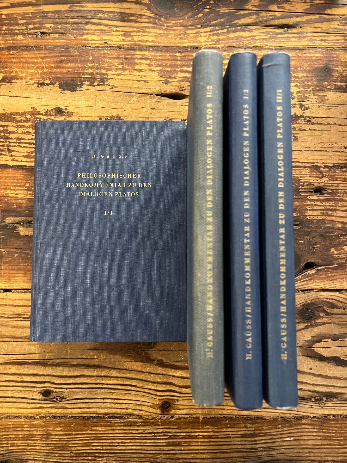 four books titled 'Philosophischer Handkommentar zu den Dialogen Platos' by H. Gauss on a wooden surface 
