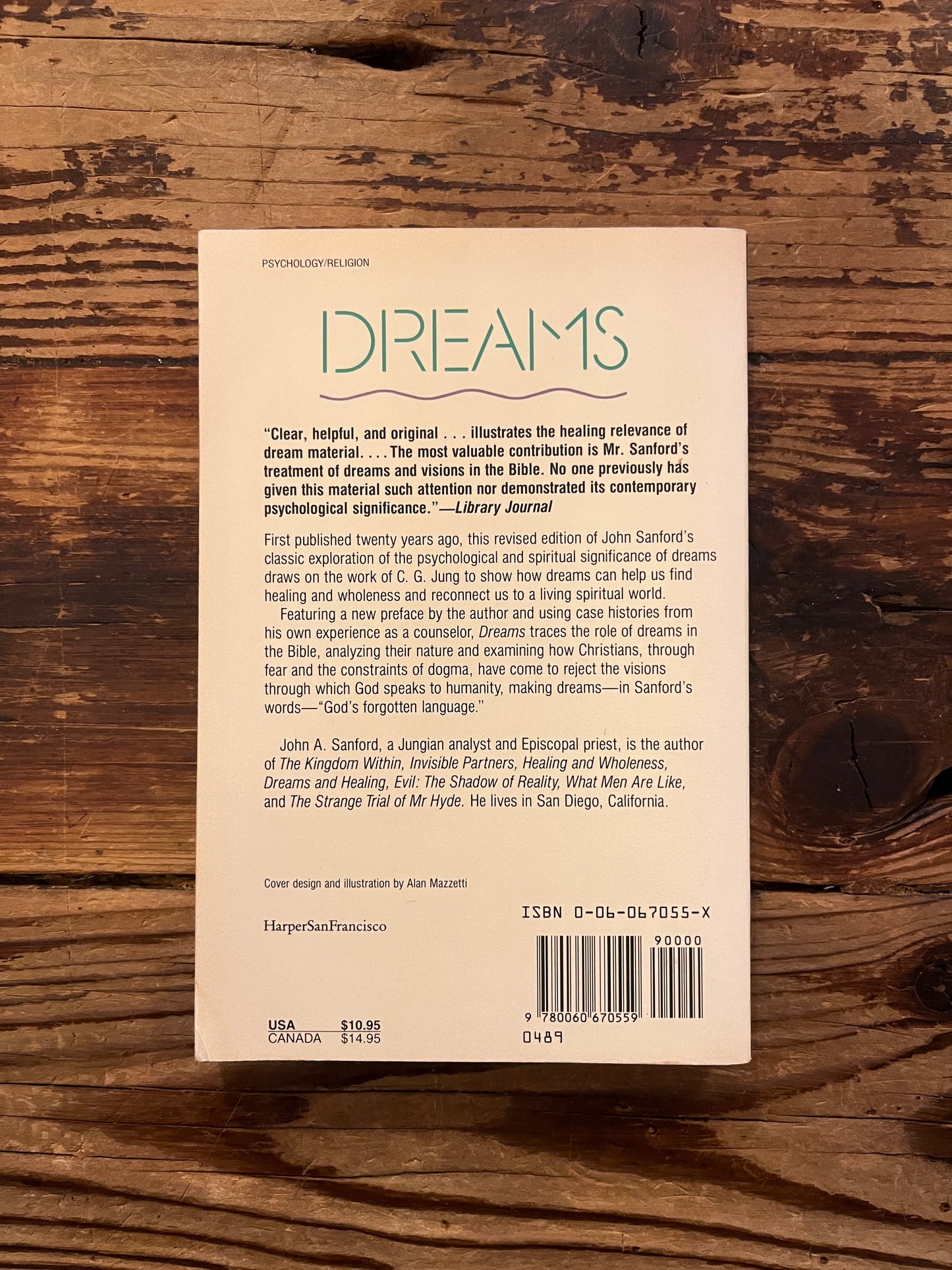 Backcover of book titled 'Dreams: God's Forgotten Language' by John A. Sanford on a wooden surface