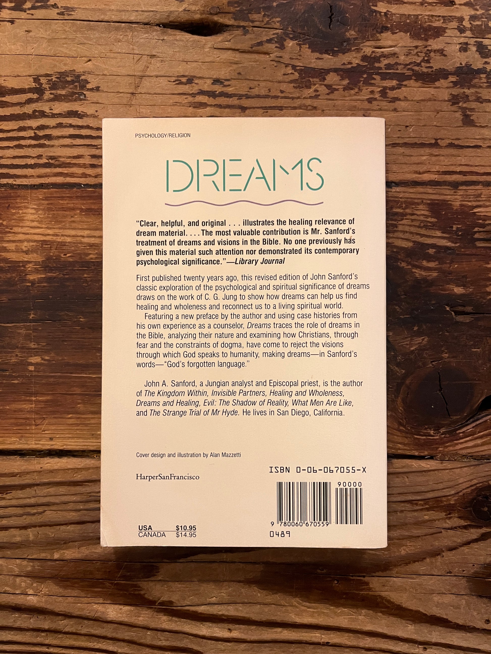 Backcover of book titled 'Dreams: God's Forgotten Language' by John A. Sanford on a wooden surface