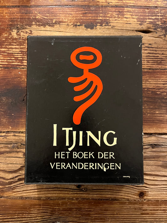 Casette met twee boeken met de titel 'I Tjing: Het Boek Der Veranderingen' op een houten achtergrond