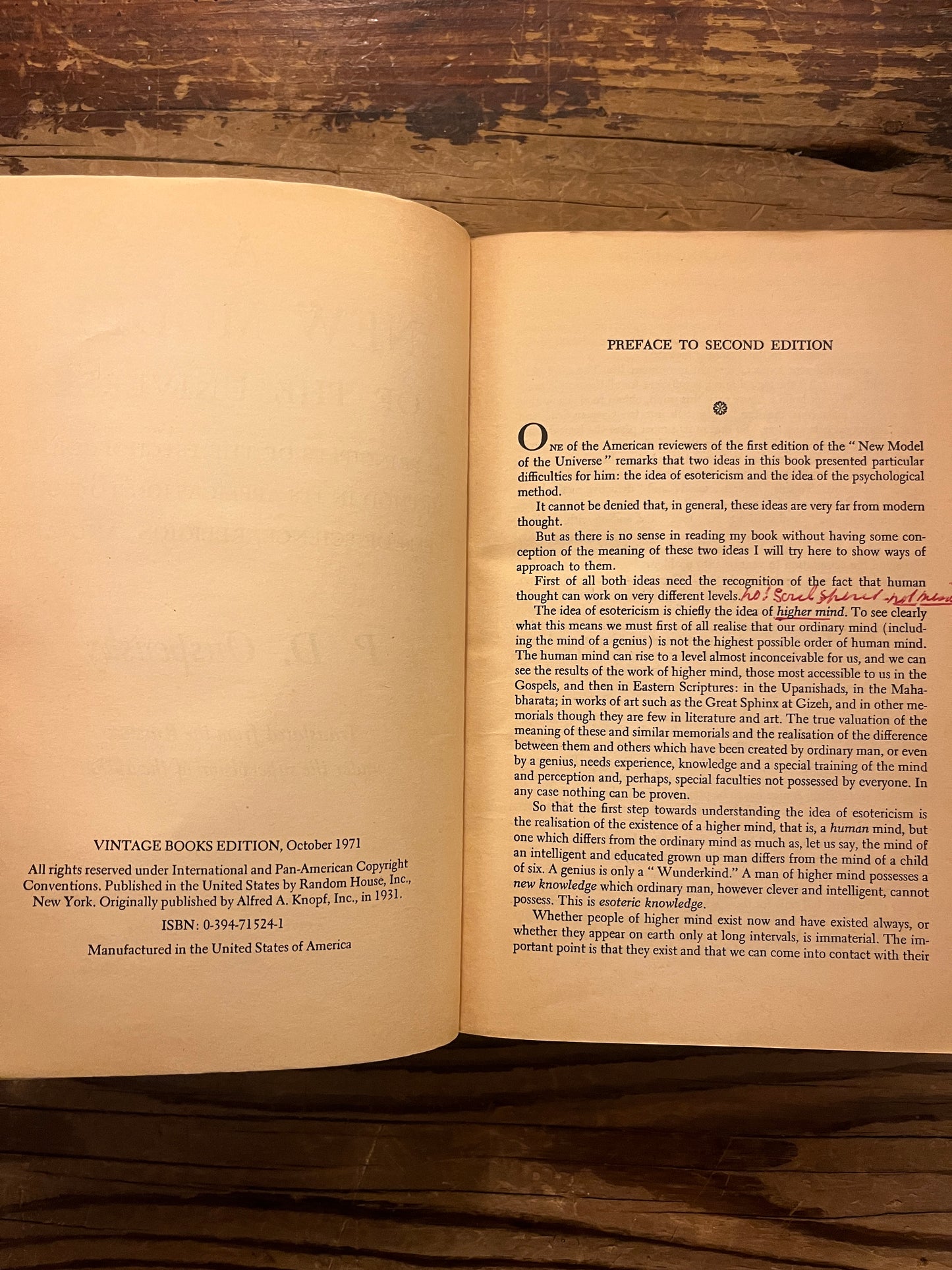 Open book titled 'A New Model of the Universe' by P.D. Ouspensky on a wooden surface