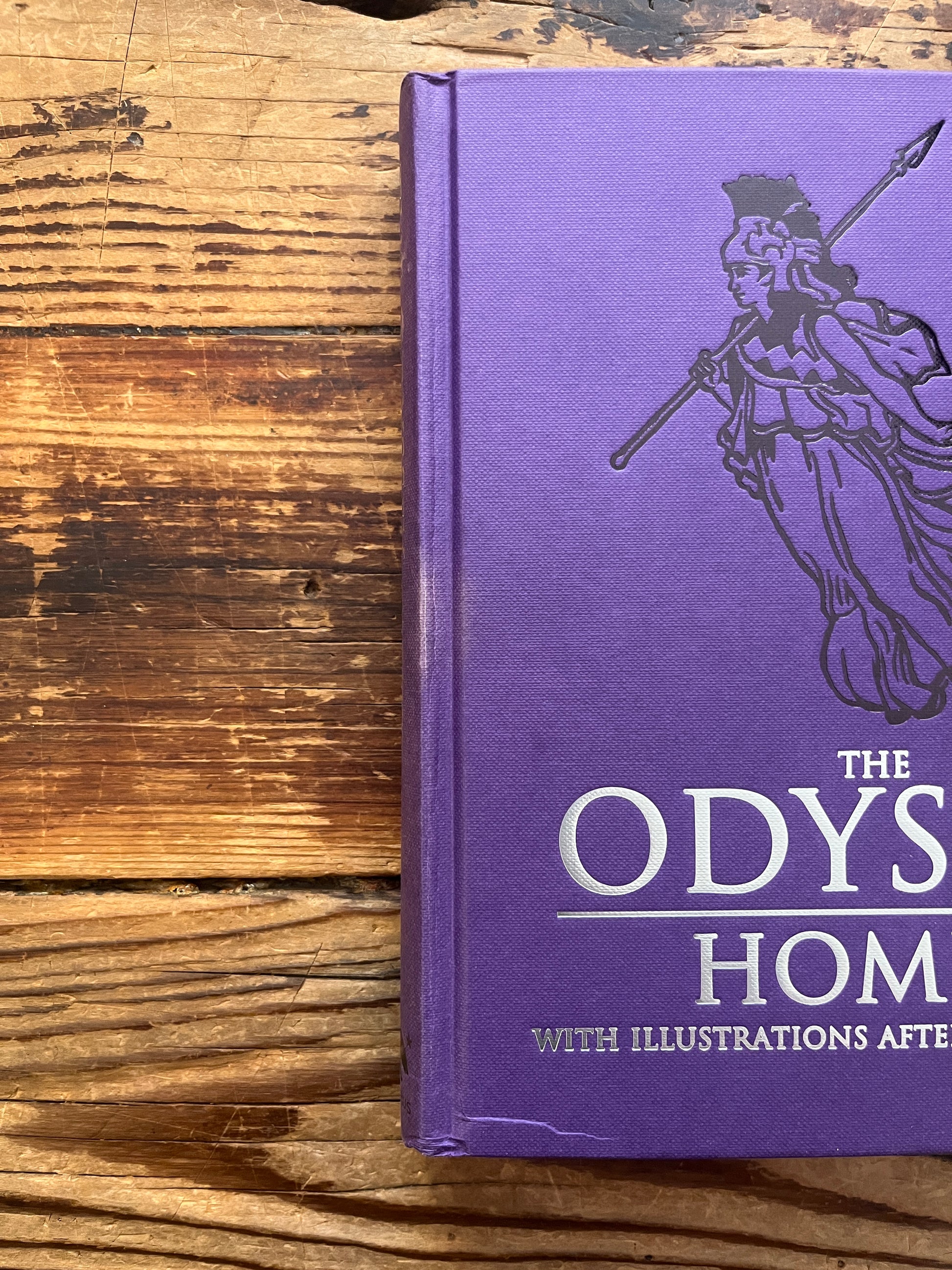 Spine and front cover of book titled 'The Odyssey' by Homer and translated by A. Pope on a wooden surface