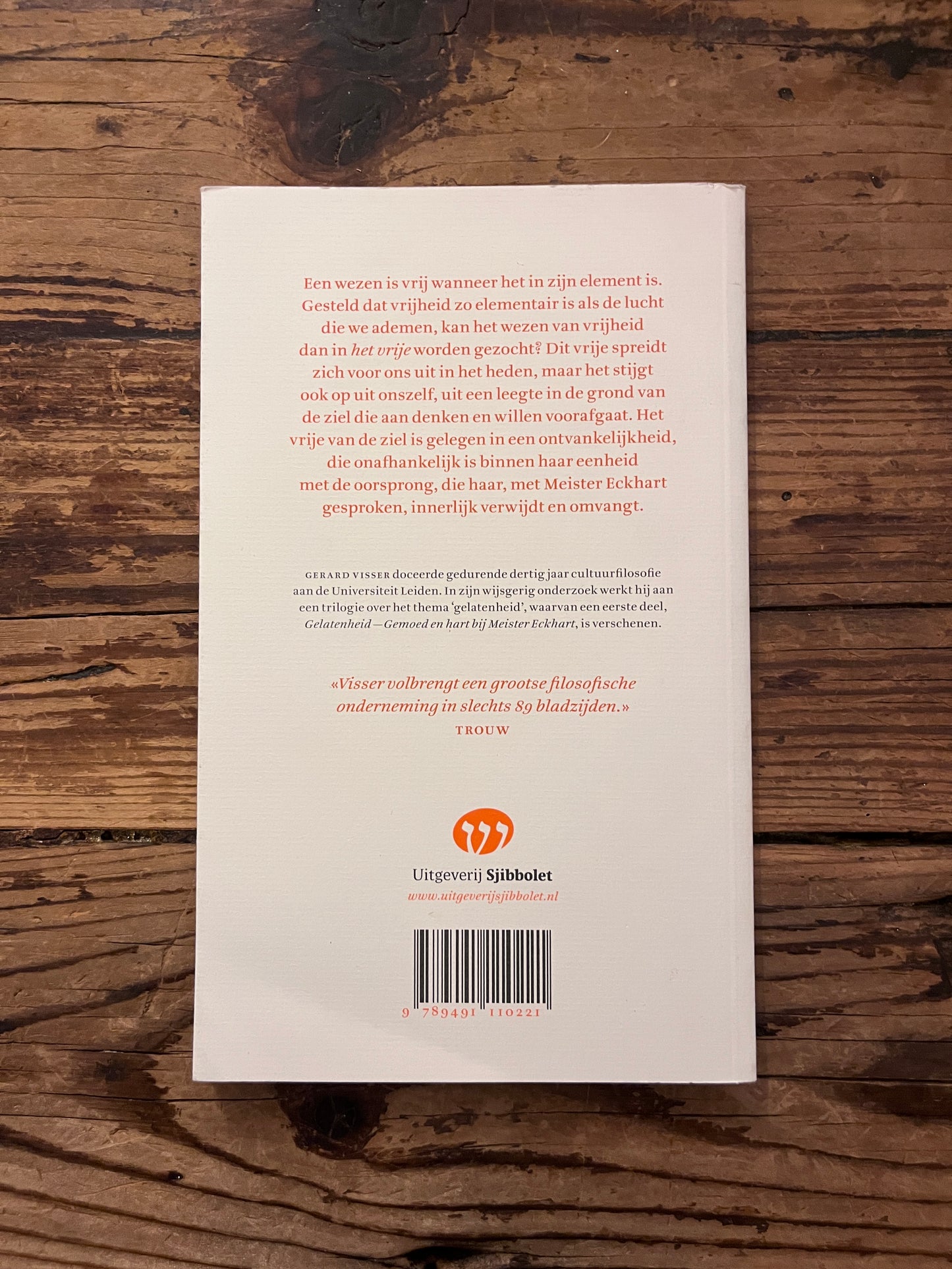 foto van de omslag van het boek "oorsprong en vrijheid" op houten achtergrond