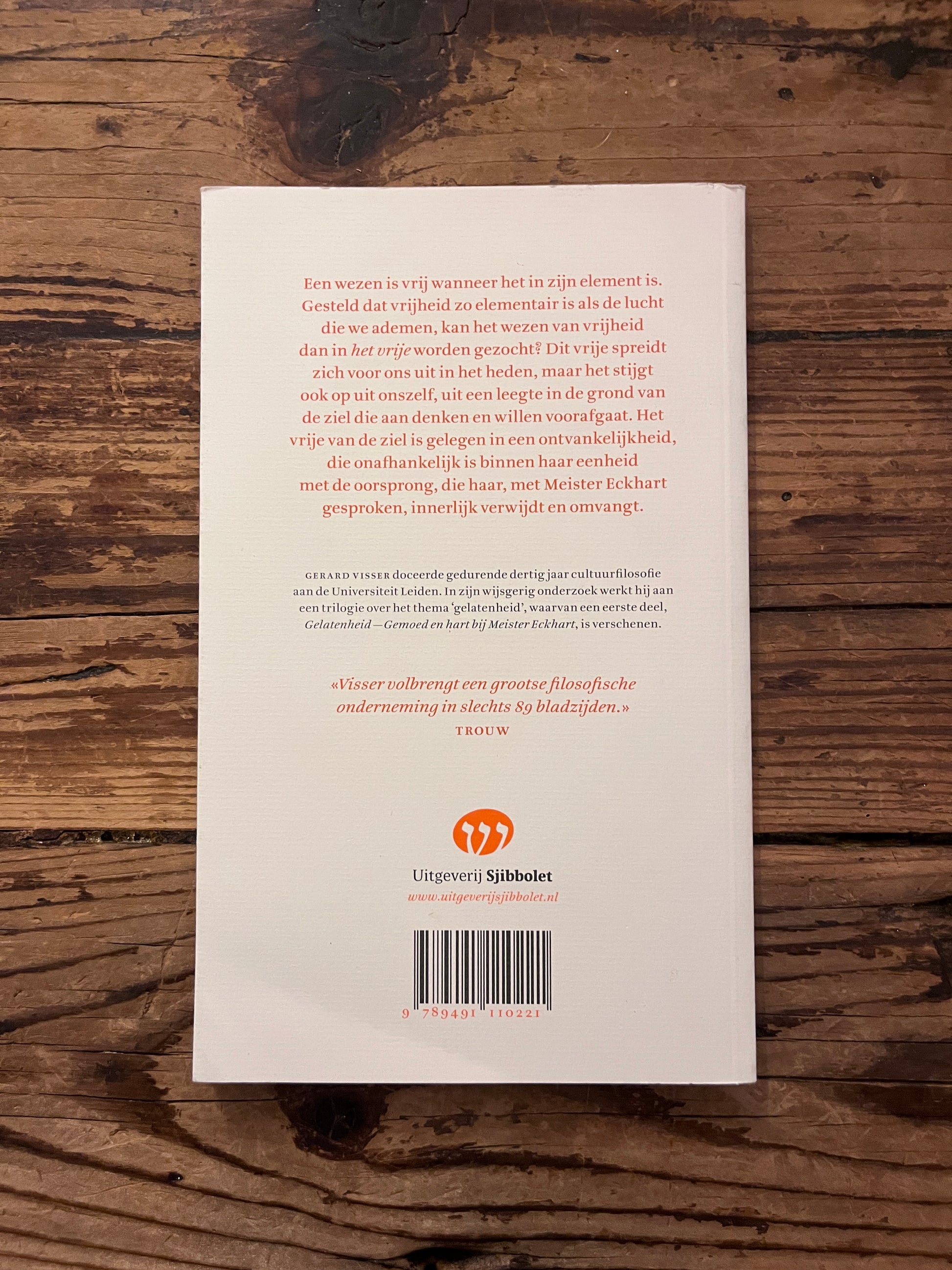 foto van de omslag van het boek "oorsprong en vrijheid" op houten achtergrond
